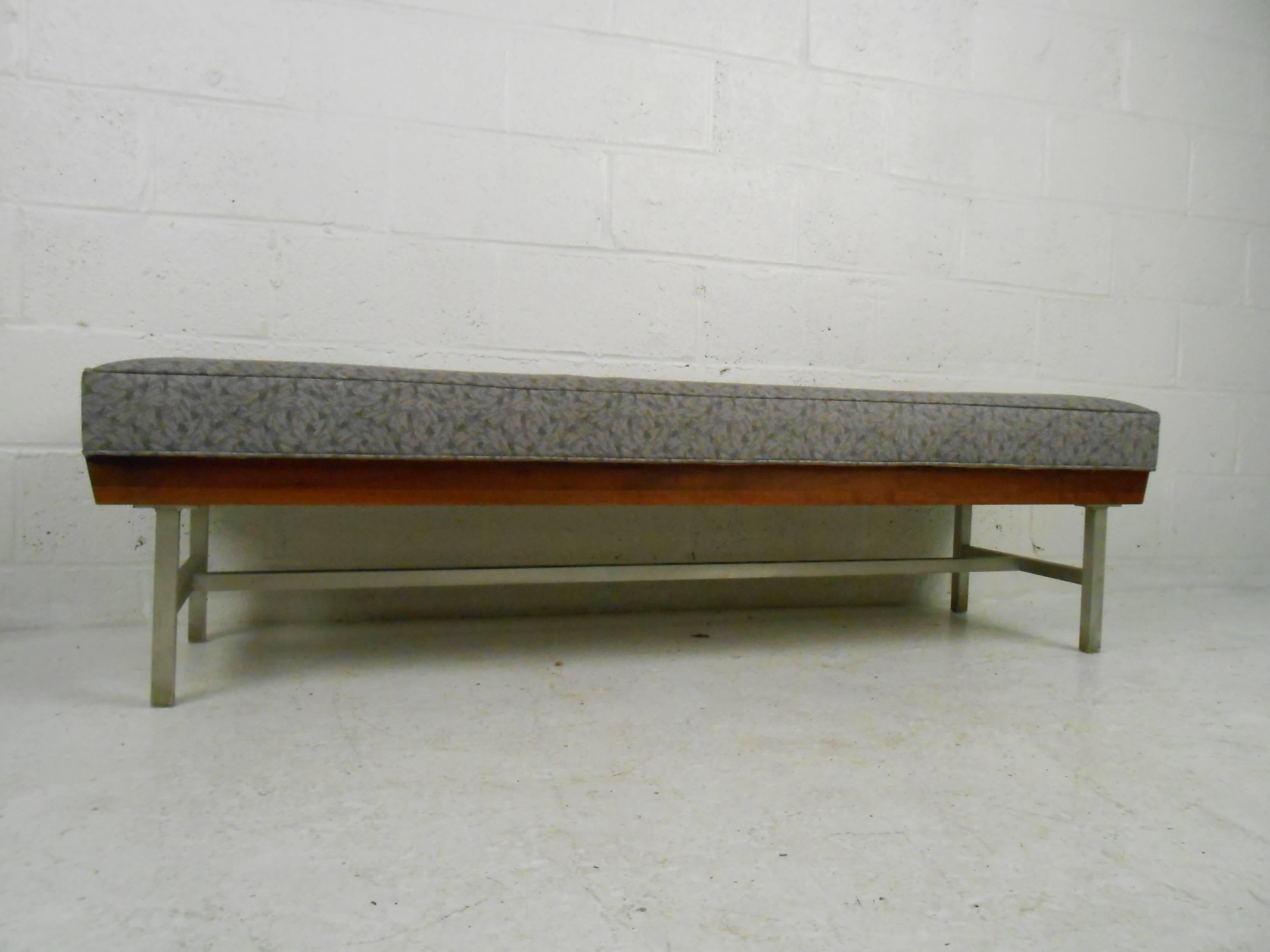 This gorgeous vintage modern bench features decorative vinyl upholstery, a wood frame, and aluminum legs. Sleek design offers comfort with its thick padded seating. This versatile midcentury piece looks incredible at the end of the bed, in the hall