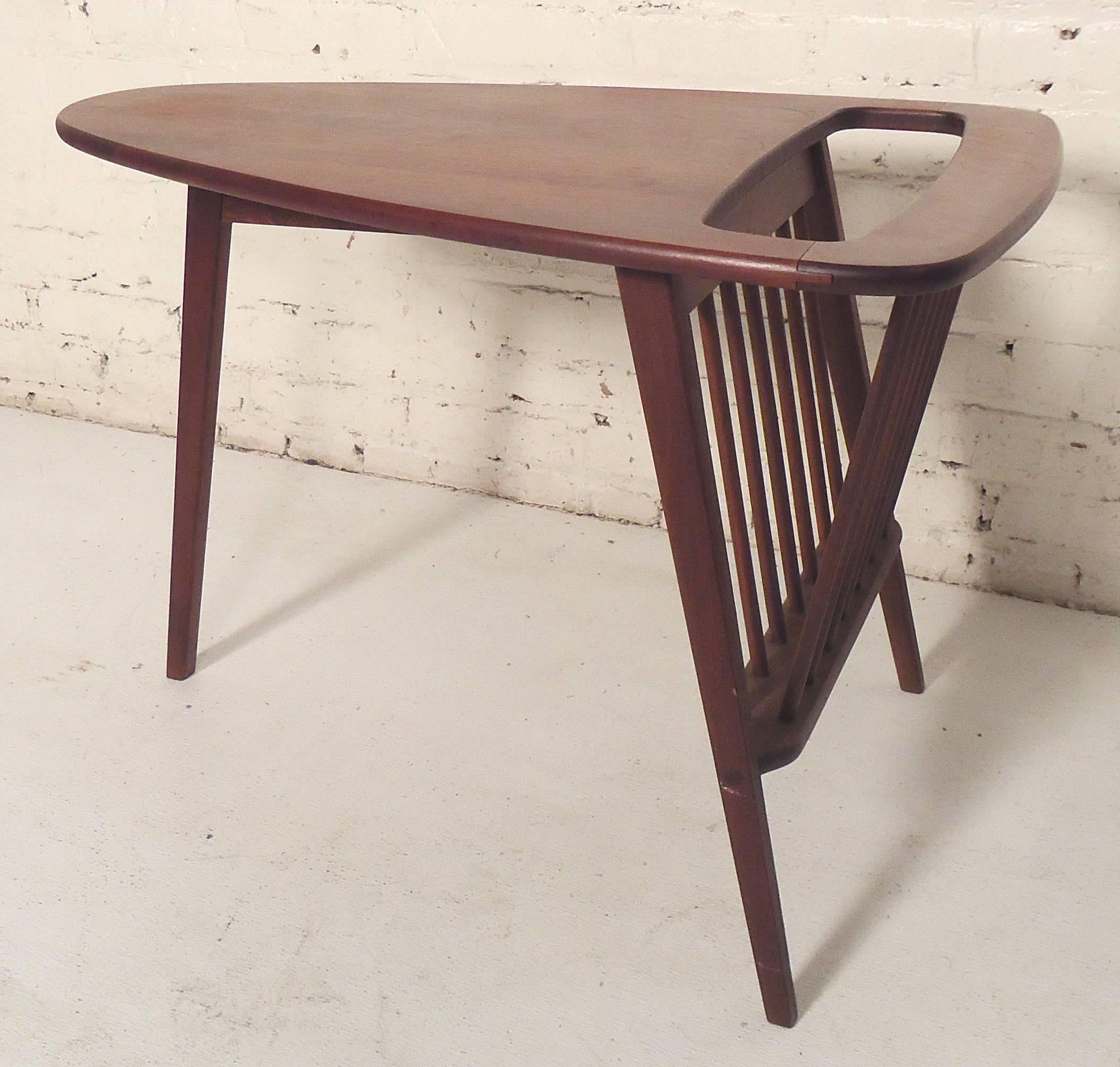 Fun midcentury design by Umanoff featuring a triangle top end table set on three legs. Deep walnut grain and spindle magazine rack.

(Please confirm item location - NY or NJ - with dealer).
 
