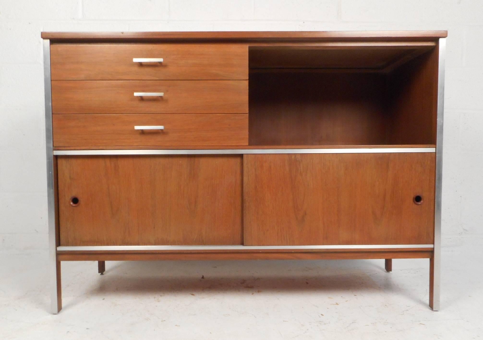 This beautiful vintage modern credenza features three hefty drawers, a storage compartment, and a lower compartment hidden by sliding doors. Sleek design with unusual circular recessed pulls on the sliding doors and unique metal drawer handles. This
