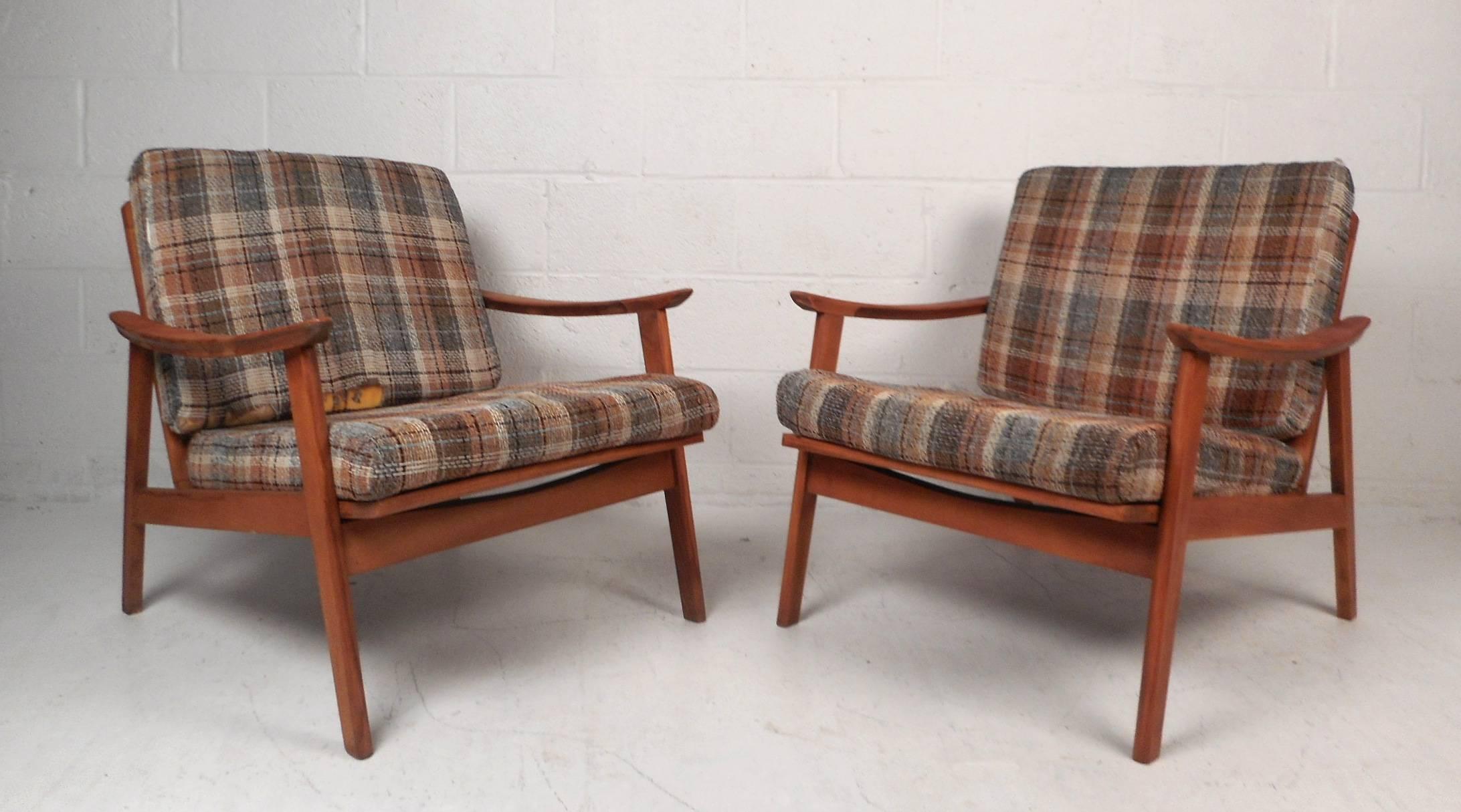 Stunning pair of vintage modern armchairs with sculpted arm rests, angled legs, and a spoked backrest. This extremely comfortable chair has overstuffed cushions upholstered in an elaborate plaid fabric. This Danish modern style pair is sure to add