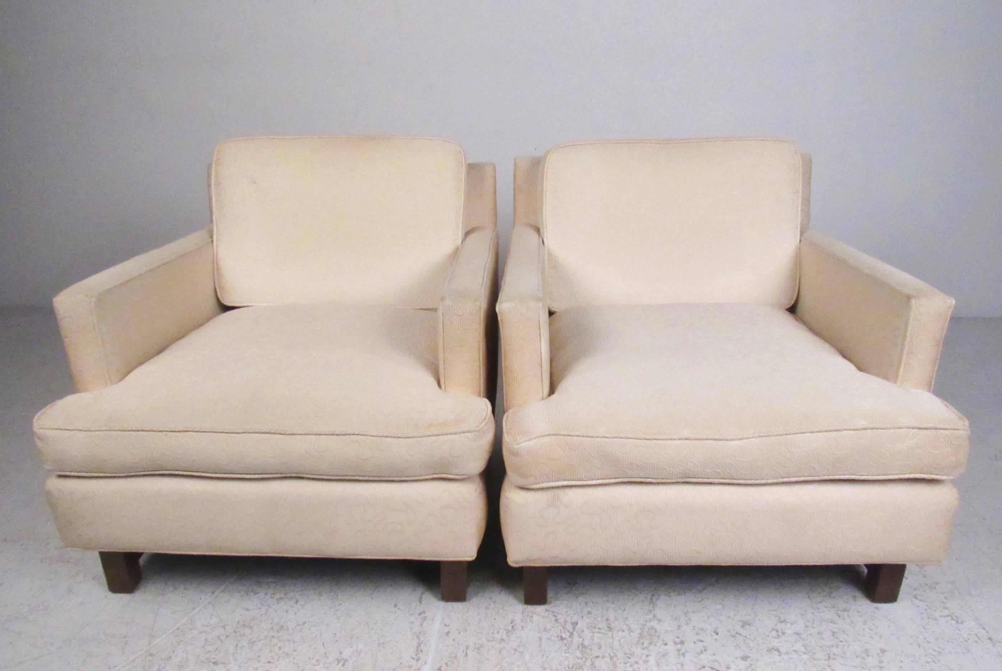 This stylish pair of vintage modern club chairs feature design similar to that by Edward Wormley for Dunbar. Hardwood legs with stretchers add to the mid-century style of this upholstered pair of oversized lounge chairs, perfect seating for home or