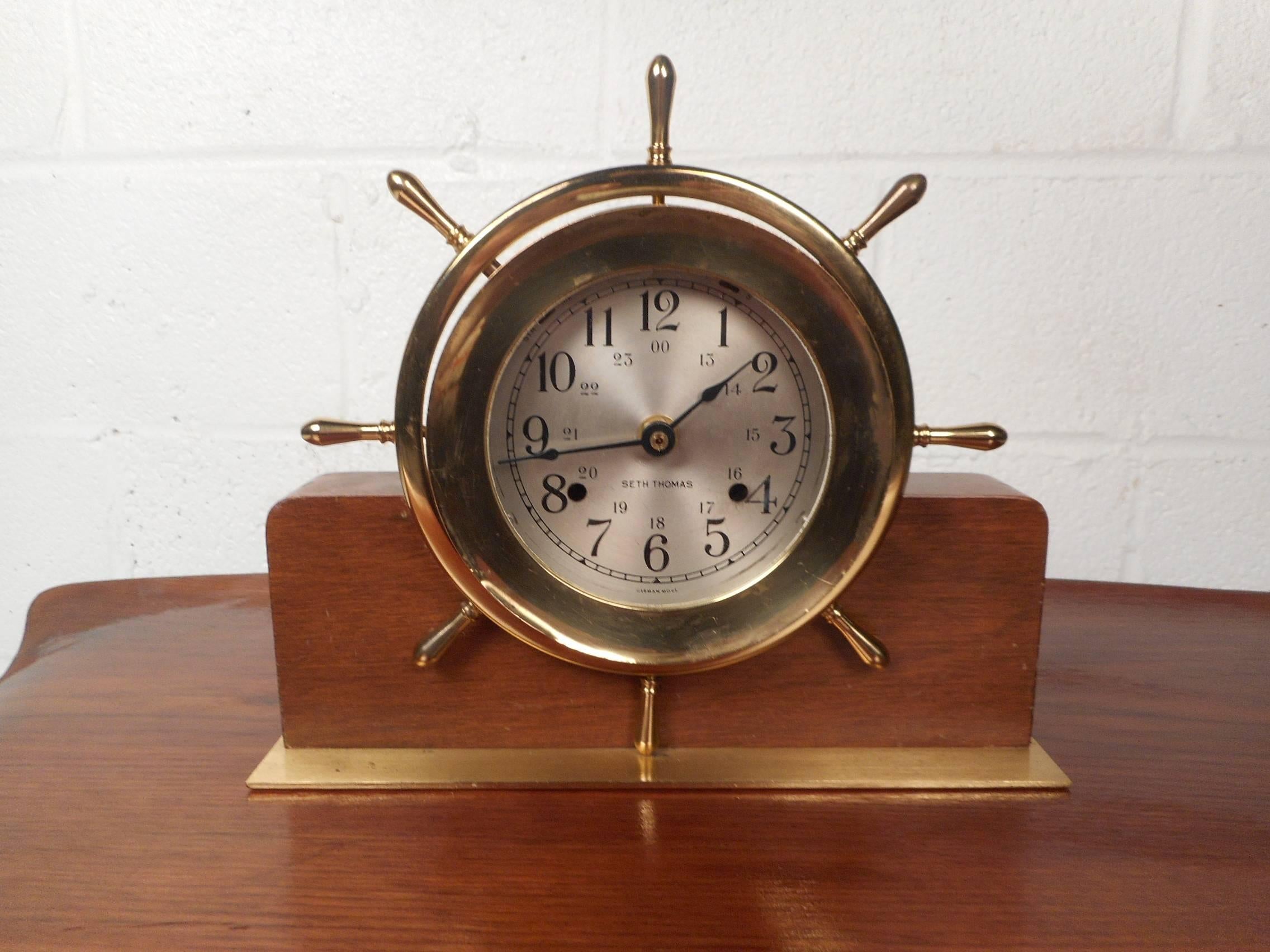 This beautiful vintage clock by Seth Thomas looks incredible on top of the mantel. Wonderful two-tone design made of brass and wood. The unusual ship wheel design and flat brass base show quality. This stunning clock makes the perfect eye catching