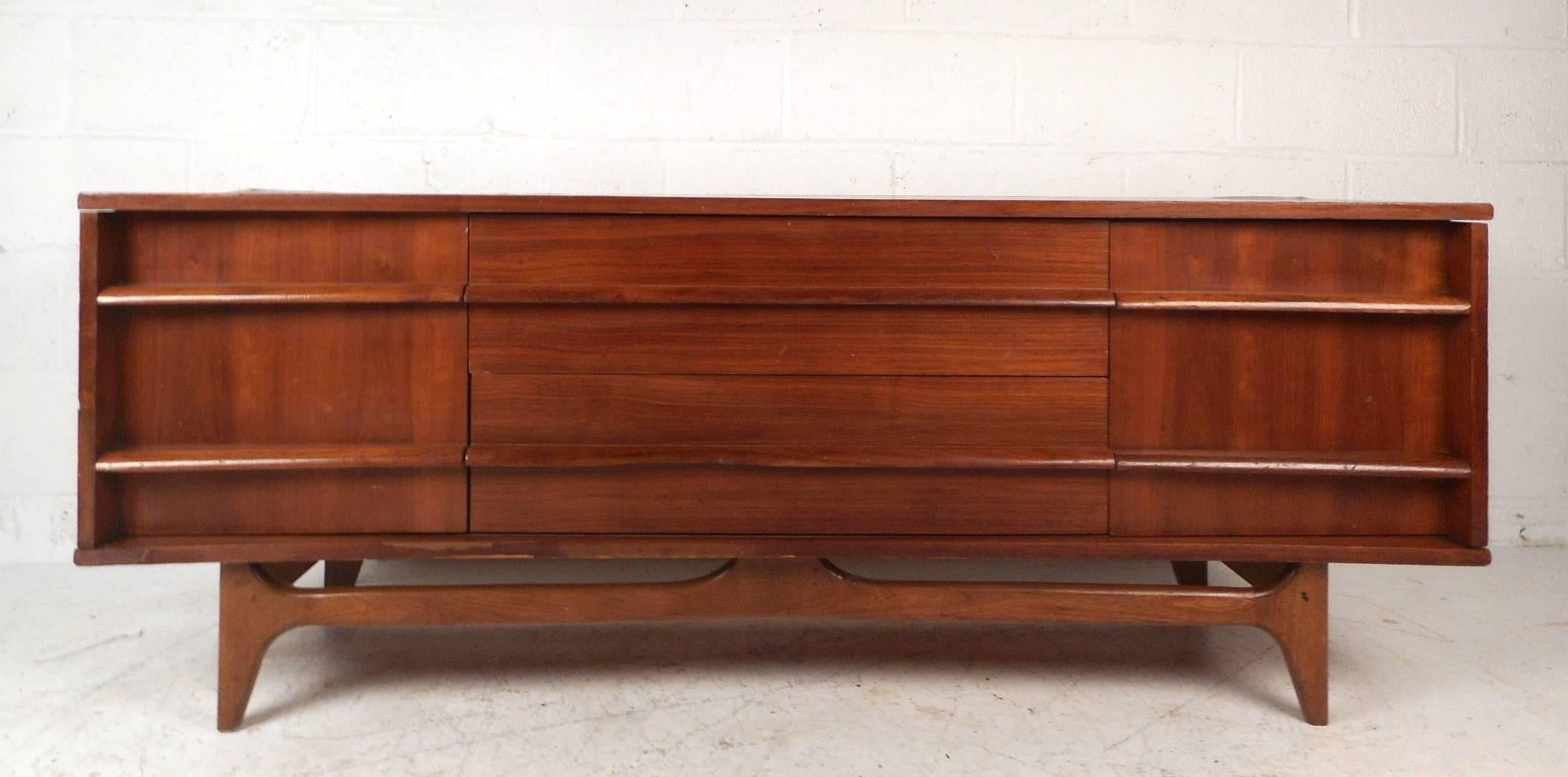 This beautiful vintage modern curved front sideboard features a dramatic curved front. The stylish design offers plenty of room for storage within its large open compartments on each side and the two hefty drawers in the middle. Extremely unique low