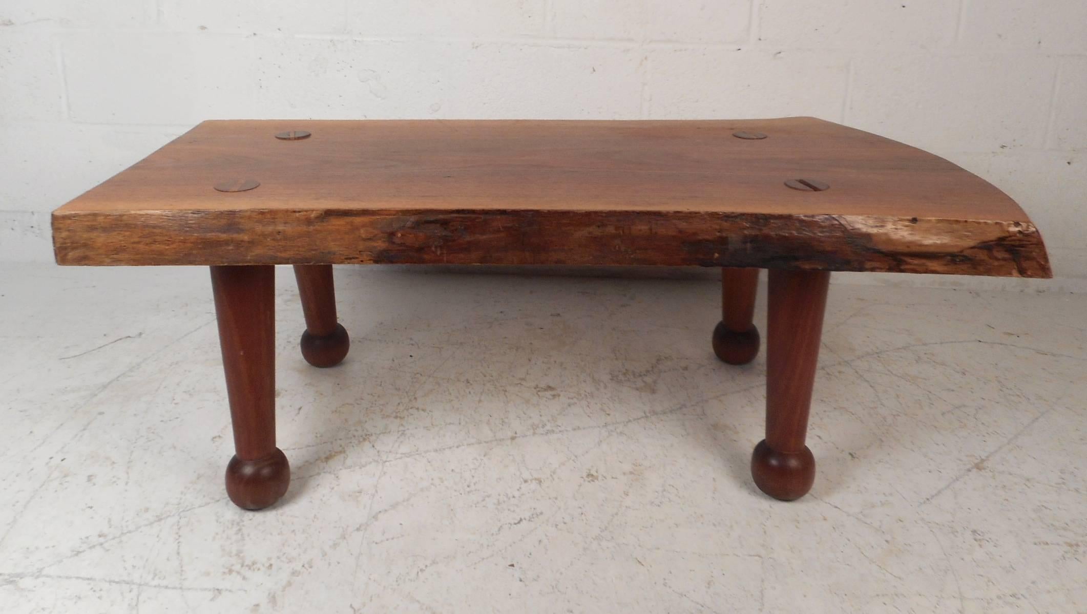 Beautiful Mid-Century Modern live edge coffee table with unusual drum stick legs and a free-form tree slab top. Quality construction with an extremely thick top, sturdy sculpted legs, and natural wood grain. This fabulous coffee table makes the