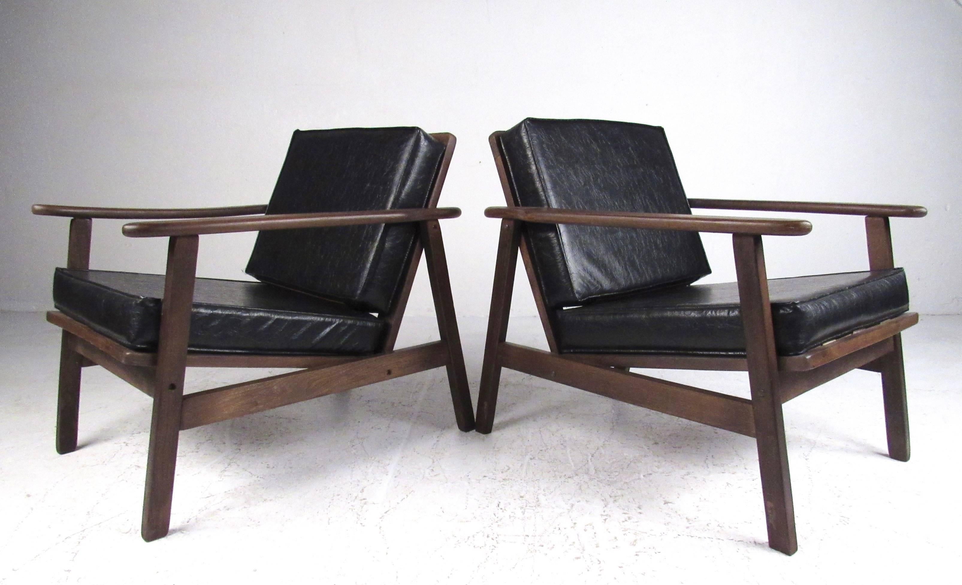 This matching pair of vintage modern lounge chairs feature textured vinyl cushions and hardwood walnut frames. This midcentury pair of armchairs make a stylish retro seating choice for any interior. Please confirm item location (NY or NJ).