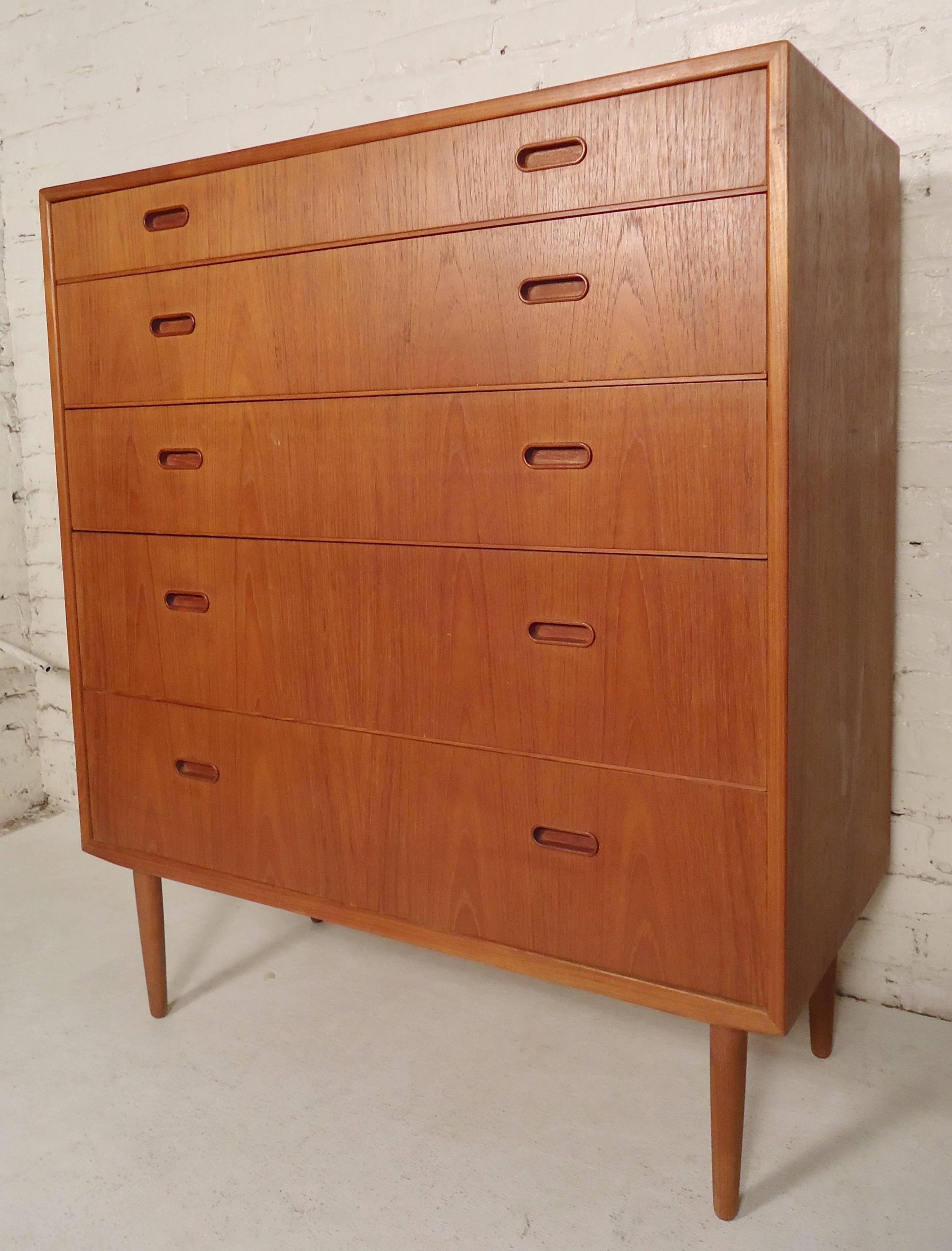 Five-drawer teak dresser with inset handles and tapered legs.

(Please confirm item location - NY or NJ - with dealer).
 