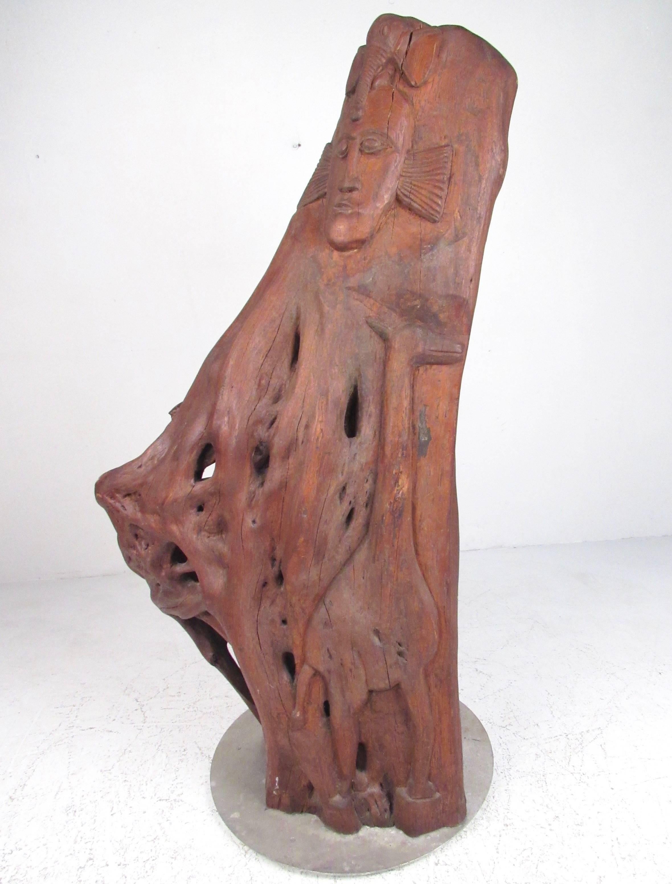 This stunning and impressive sculpted live edge tree trunk is the perfect mix of hand carved artisan detail and natural beauty. African tribal motif includes several animals and insects worked into the piece, all mounted on aluminum base. Standing
