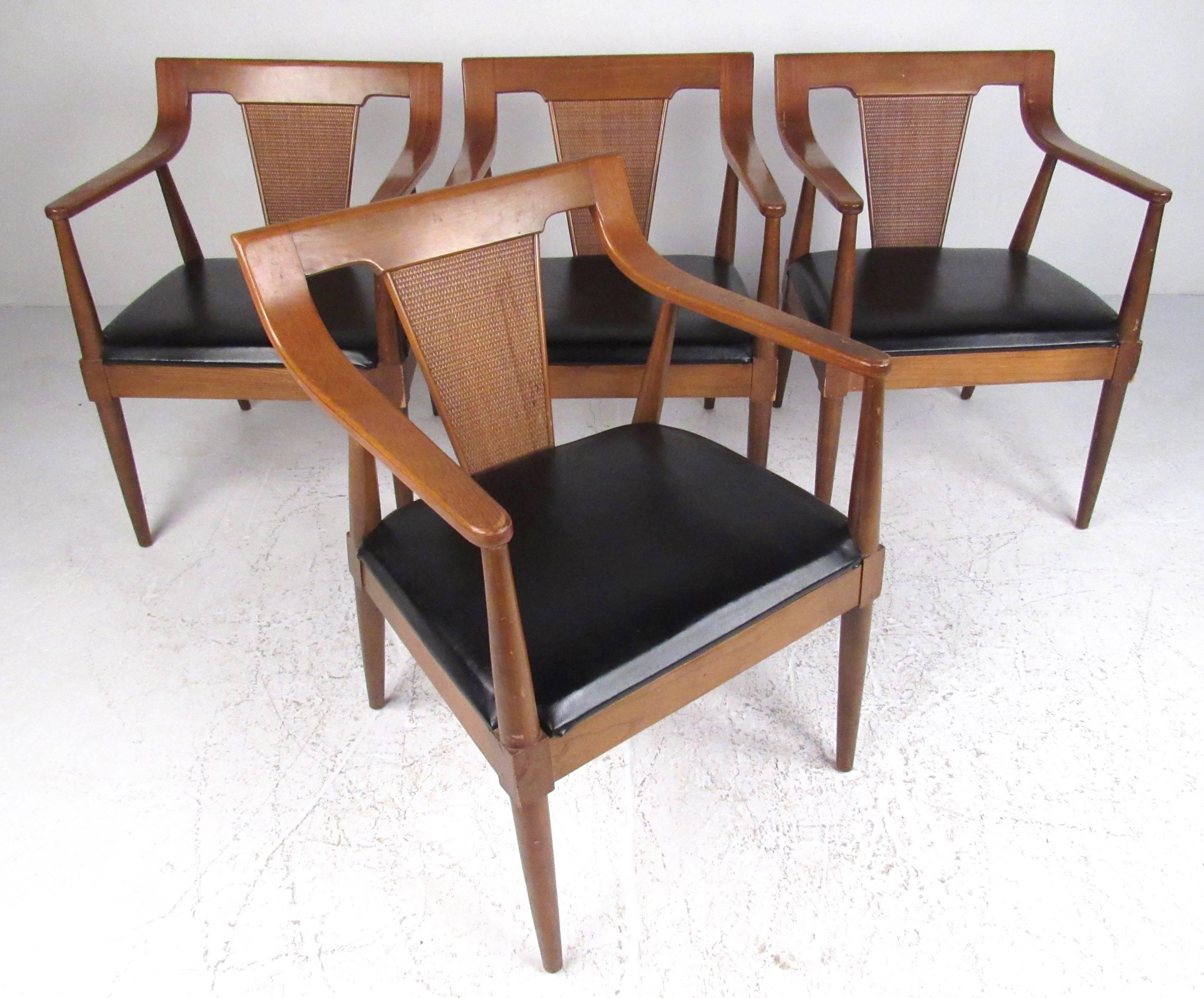 This unique set of four armchairs feature sculpted American walnut construction, spacious vinyl seats, and stylish Mid-Century Modern design. Sturdy set of arm chairs by Basic Witz make the perfect addition to any dining room or office. Please
