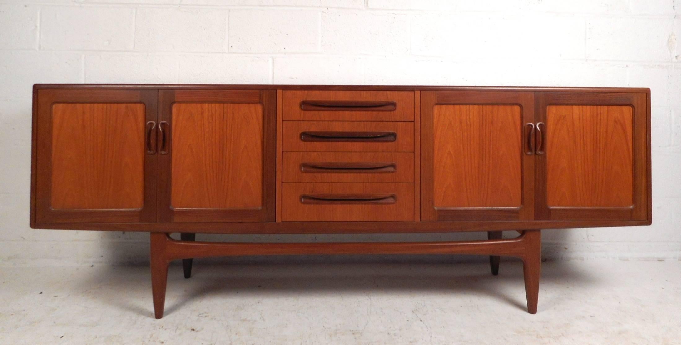 This beautiful vintage modern sideboard features plenty of room for storage within its four hefty drawers and two large storage compartments hidden by cabinet doors. Sleek two-tone design with unique carved pulls and tapered legs adding to the