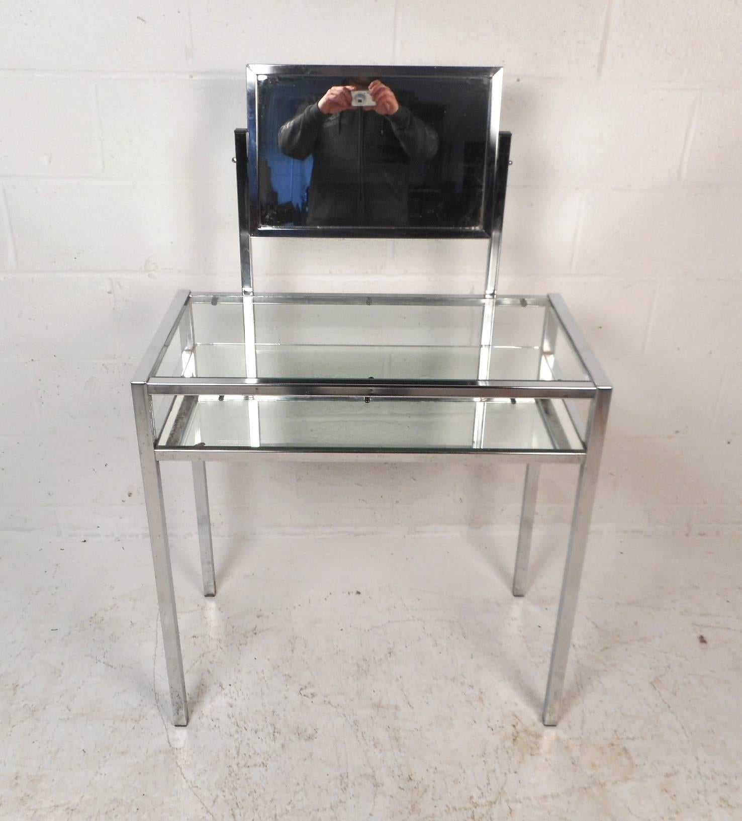 This beautiful vintage modern vanity features a heavy chrome frame with two tiers and a mirror. The unique design has a lower tier with a mirror top and a clear glass tabletop to set items on. Stylish console table with a mirror that swivels