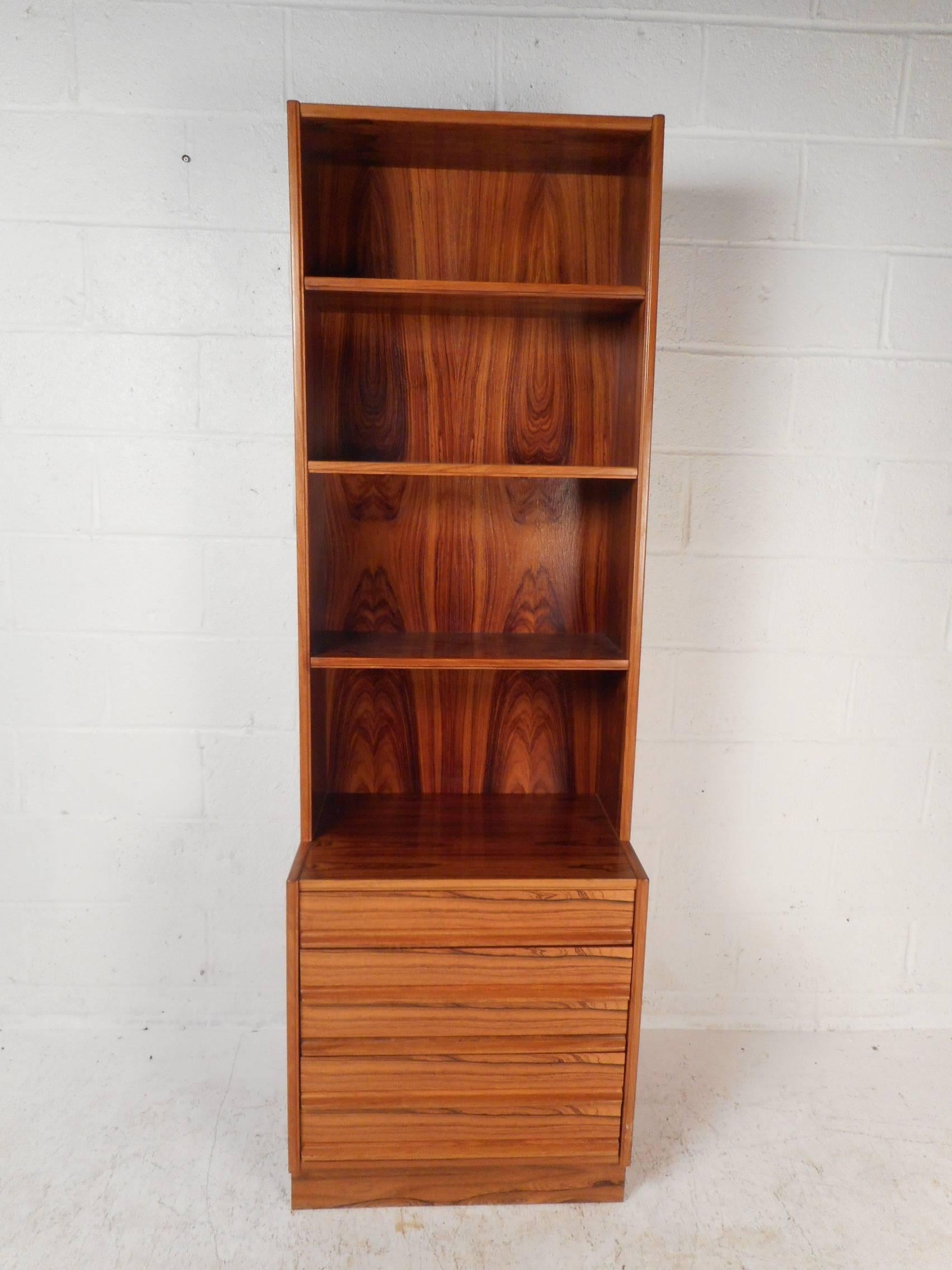 This beautiful vintage modern bookshelf features four wide shelves and five drawers on the bottom with sculpted pulls. This wonderful case piece offers plenty of room for storage while displaying items on the top. This versatile midcentury piece has