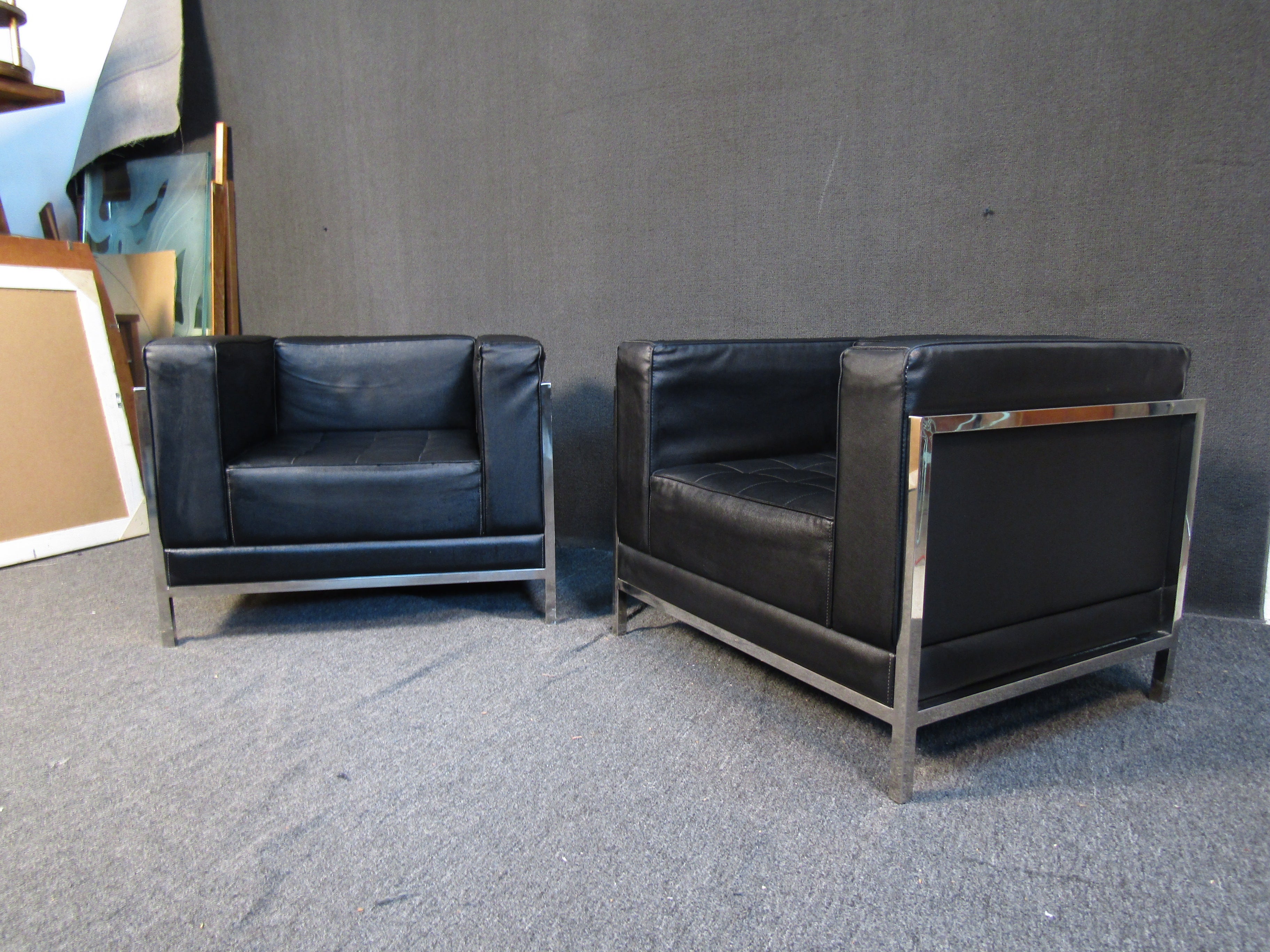 This pair of elegant club chairs combines dark rich leather with a bright chrome frame. An oversized cushioned design provides comfortable seating in a Mid-Century Modern design. Please confirm item location with seller (NY/NJ).