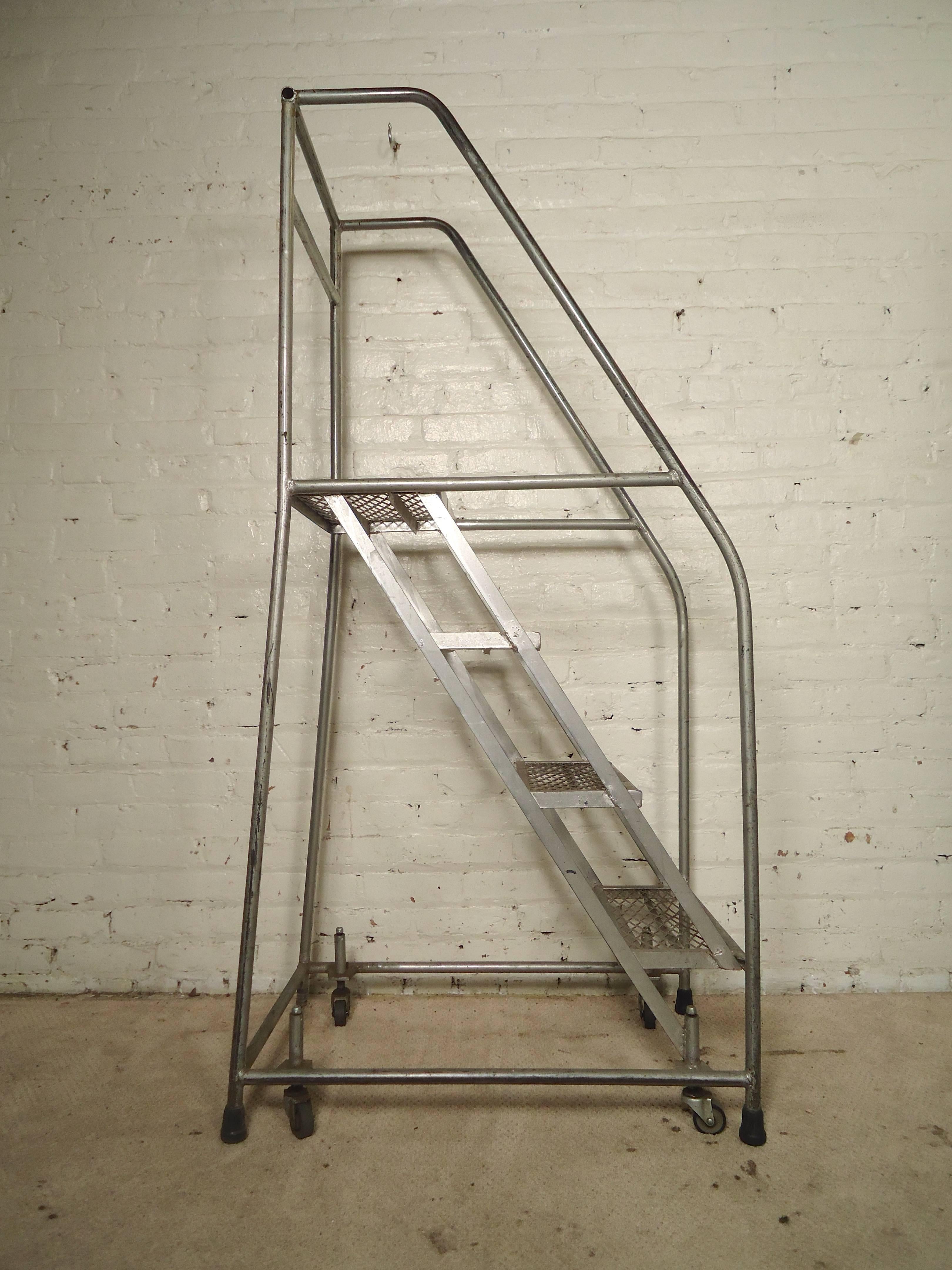 Single four step metal rolling ladder with handrails and top step railing. Features spring loaded swivel casters that retract under user’s weight. Top step is 39
