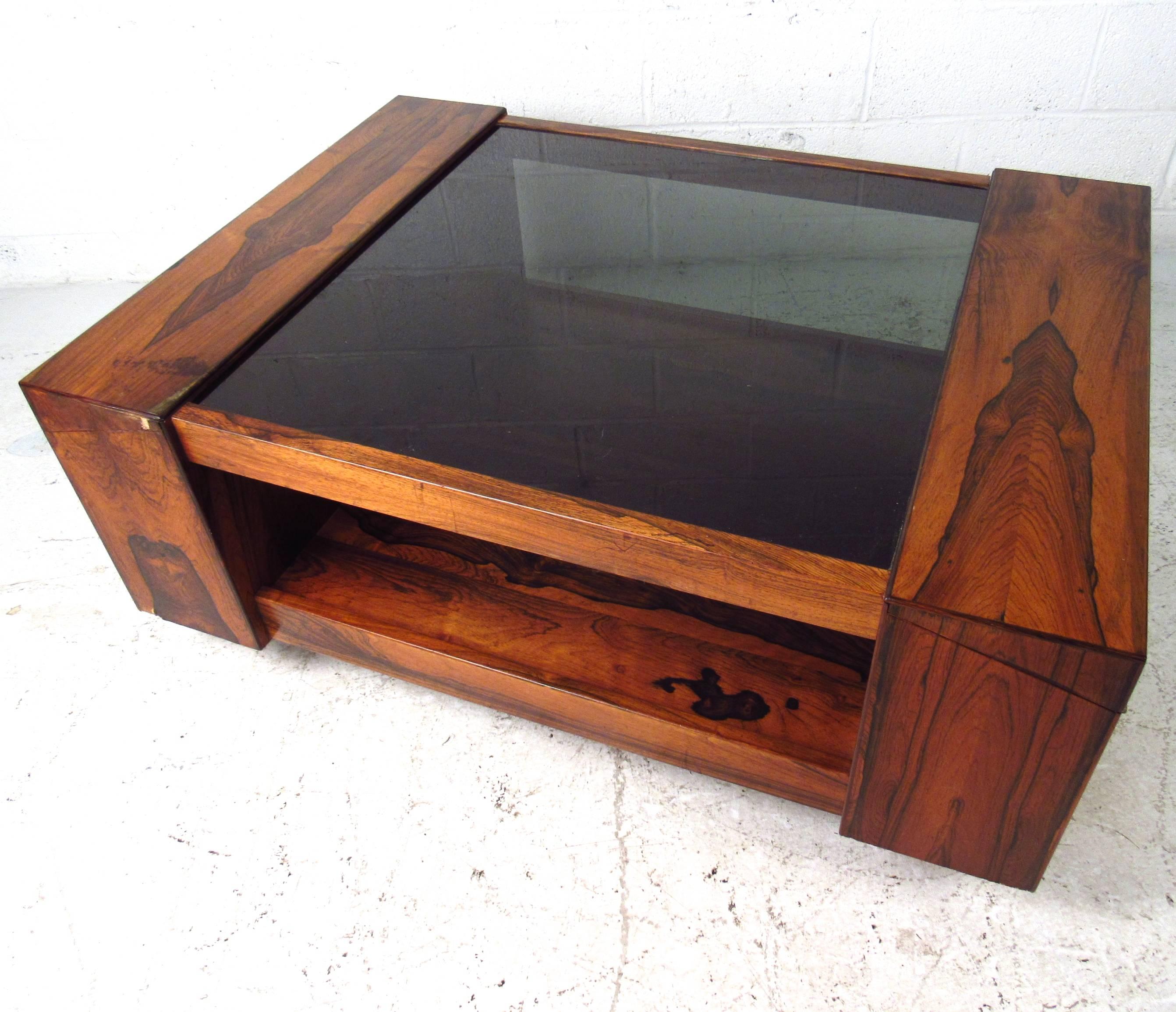 This unique smoked glass coffee table features hideaway storage, vintage rosewood finish, and unique chrome feet. This substantial table is the perfect addition to any interior. Please confirm item location (NY or NJ).