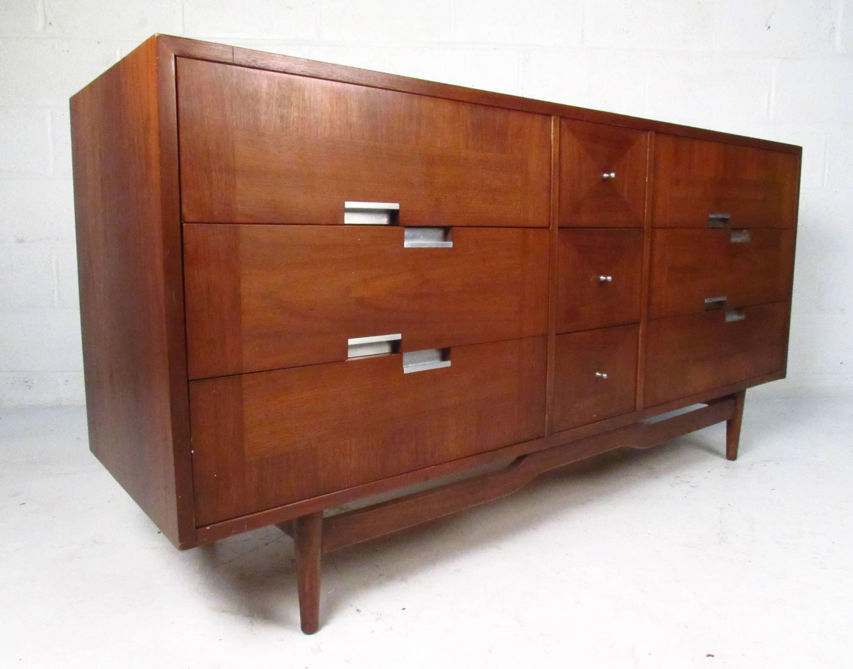 This beautiful walnut dresser features unique mid-century drawer pulls, banded veneer drawer fronts, and an assortment of drawers perfect for organizing in any room. Unique in-lays add to its appeal, while stretchers add to its durability. Please