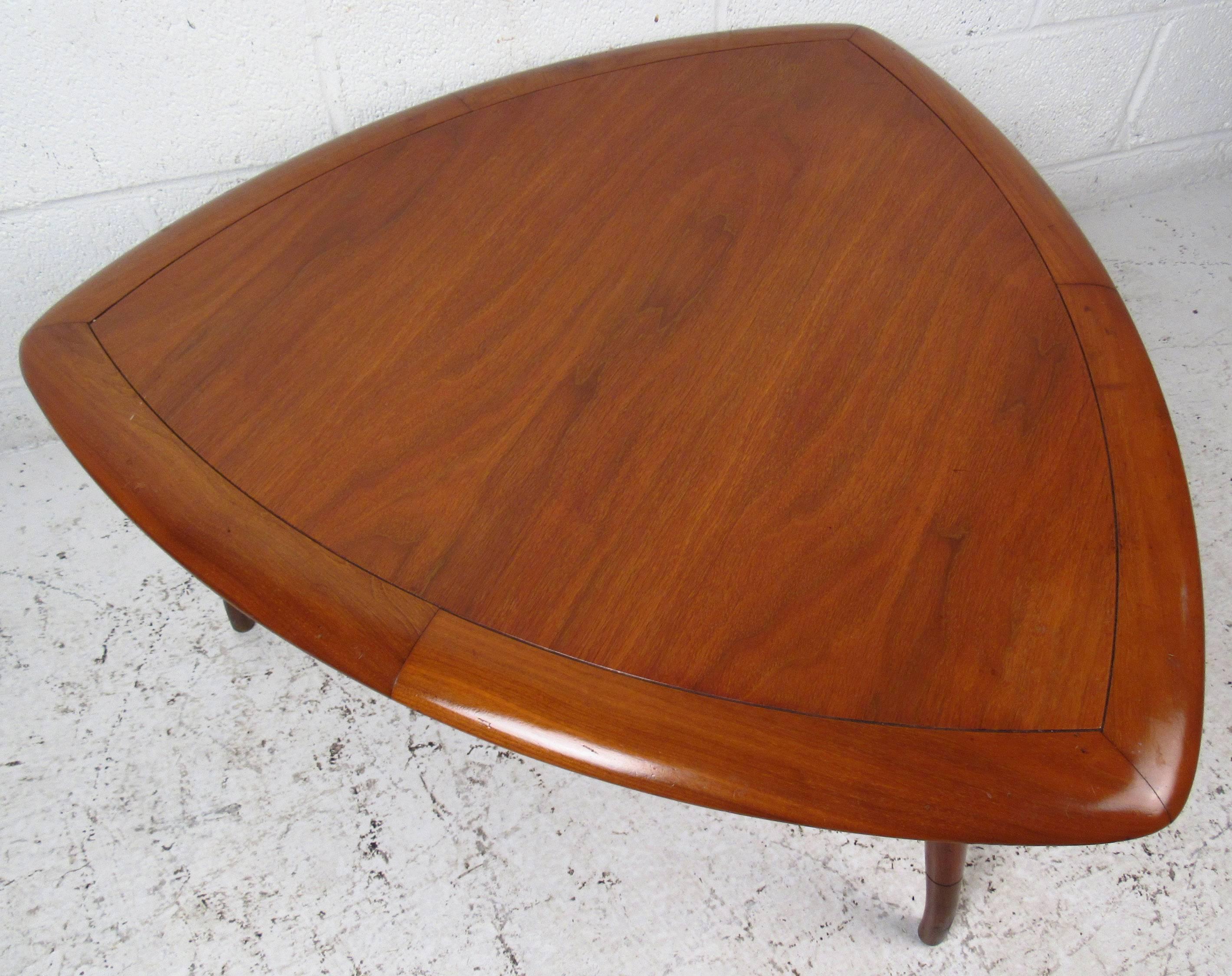 Vintage-modern coffee table by Tomlinson, features triangular top, walnut grain and beautifully sculpted legs. This unusual piece makes the perfect eye catching addition to any modern interior. Please confirm item location (NY or NJ).

Please