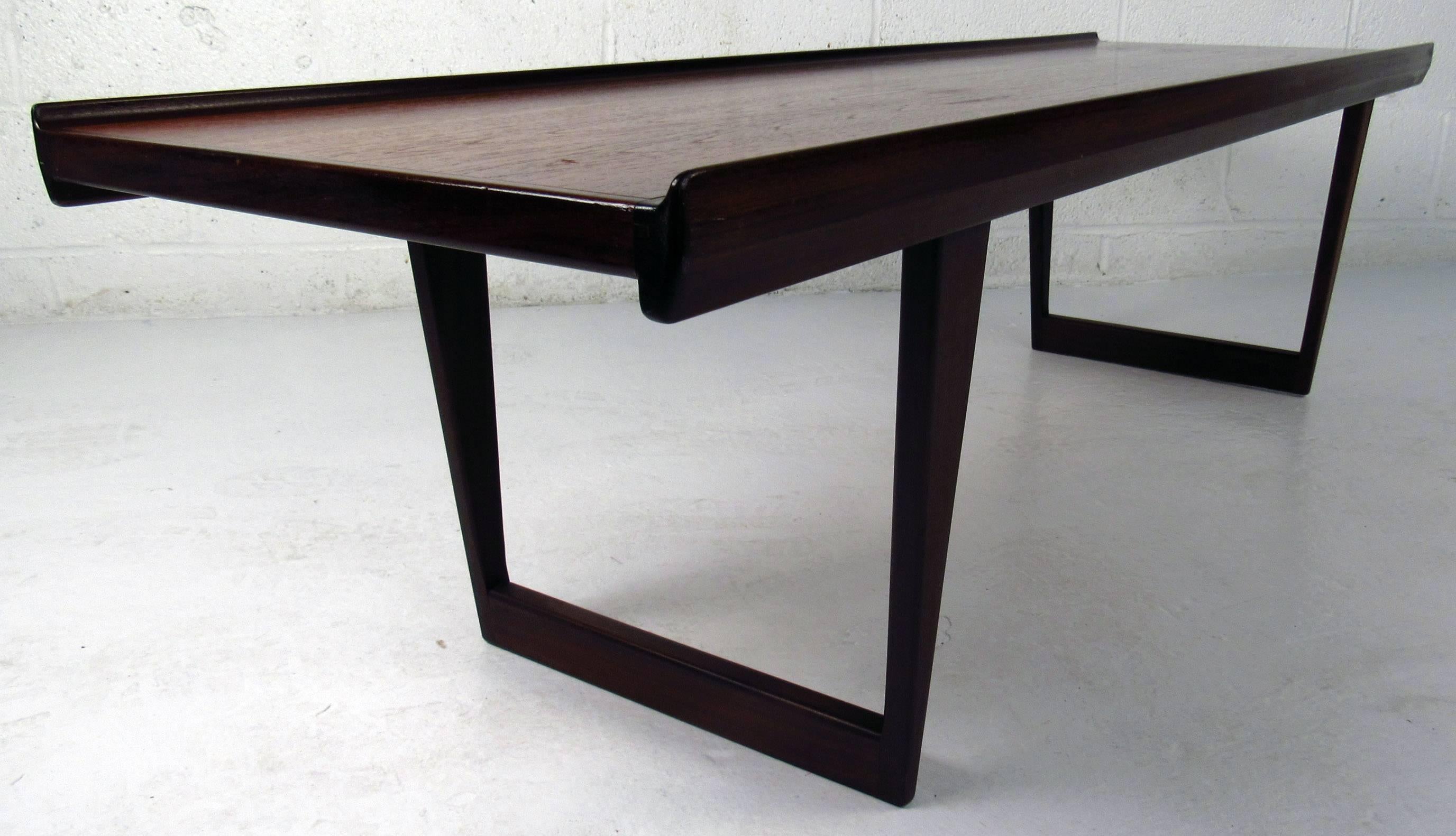 Vintage-modern teak coffee table with raised lip along both sides, sculpted sled legs and beautiful wood grain. Perfect cocktail table showcases quality mid-century construction from Scandinavia. 

Please confirm item location NY or NJ with dealer.