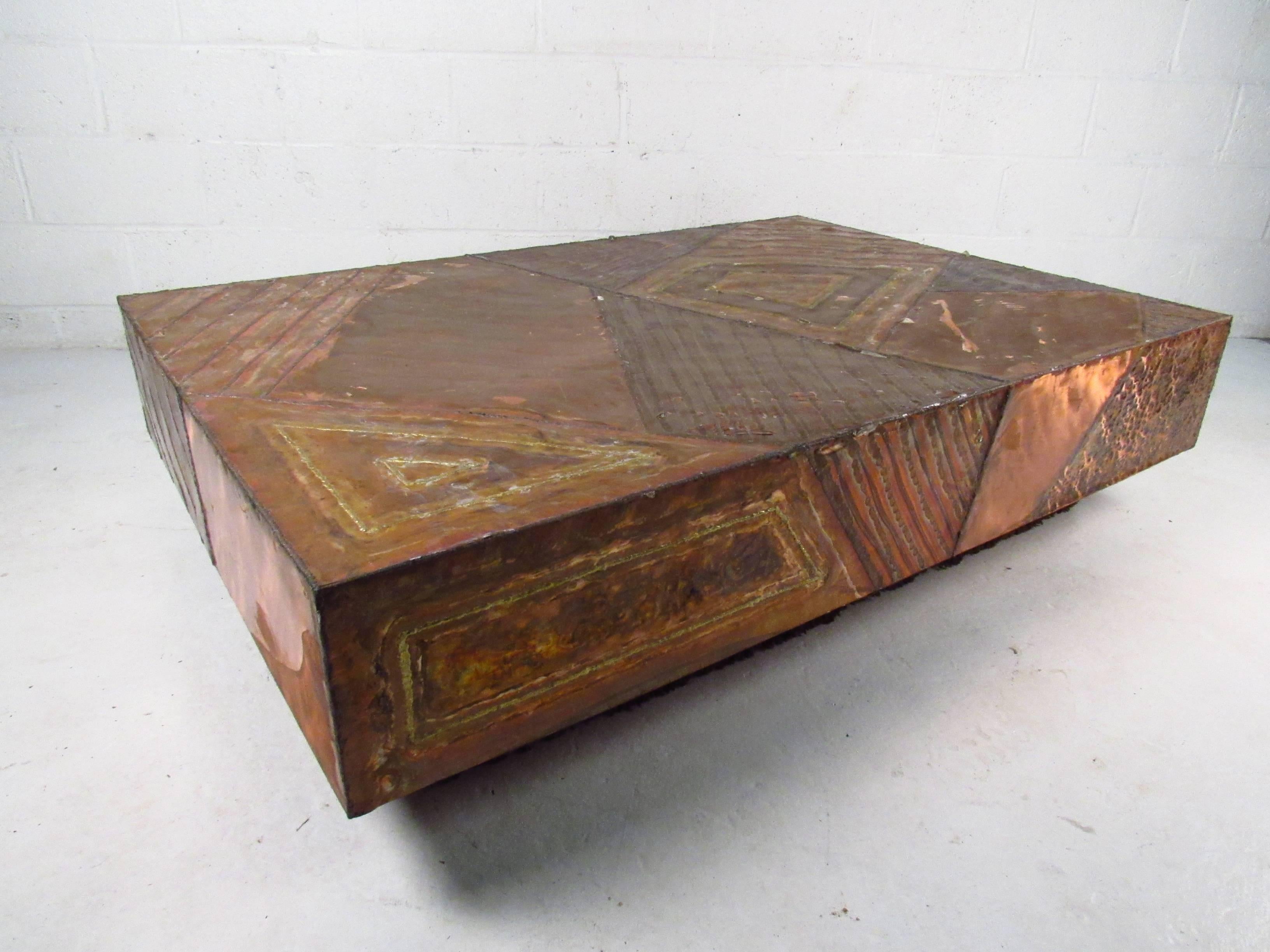 This large hammered copper table features a uniquely textured top with built in base lighting. Substantially sized, this unique piece makes an impressive mid-century addition to any interior. Base trim is carpeted in dark brown. Please confirm item