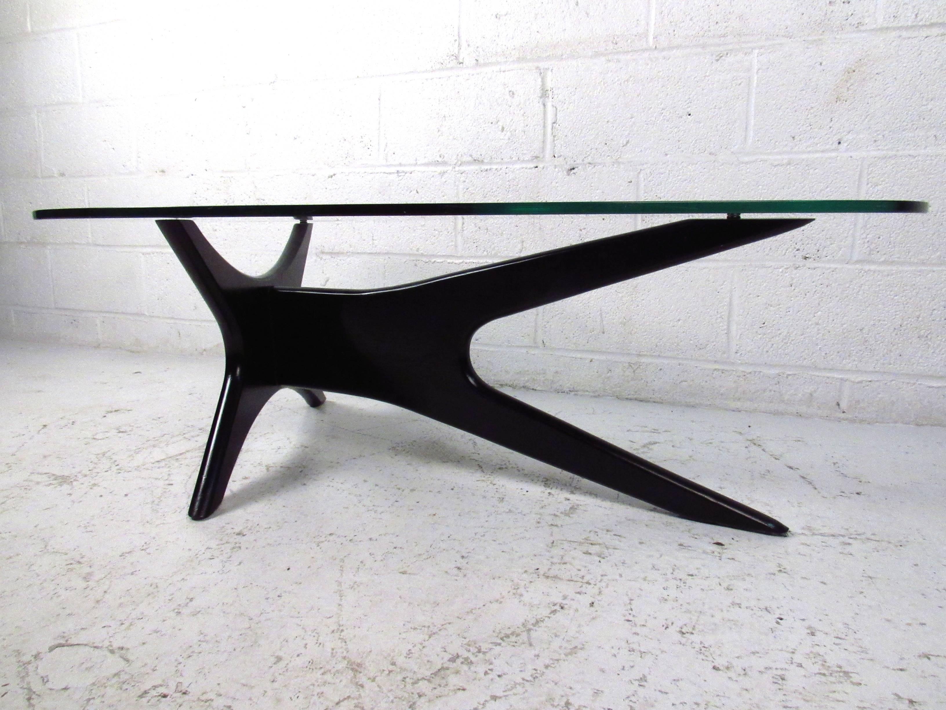 This vintage coffee table is a wonderful representation of midcentury style, complete with sculpted base and kidney shaped top. This stylish Adrian Pearsall style coffee table features a shapely glass top and atomic modern style lacquered base.