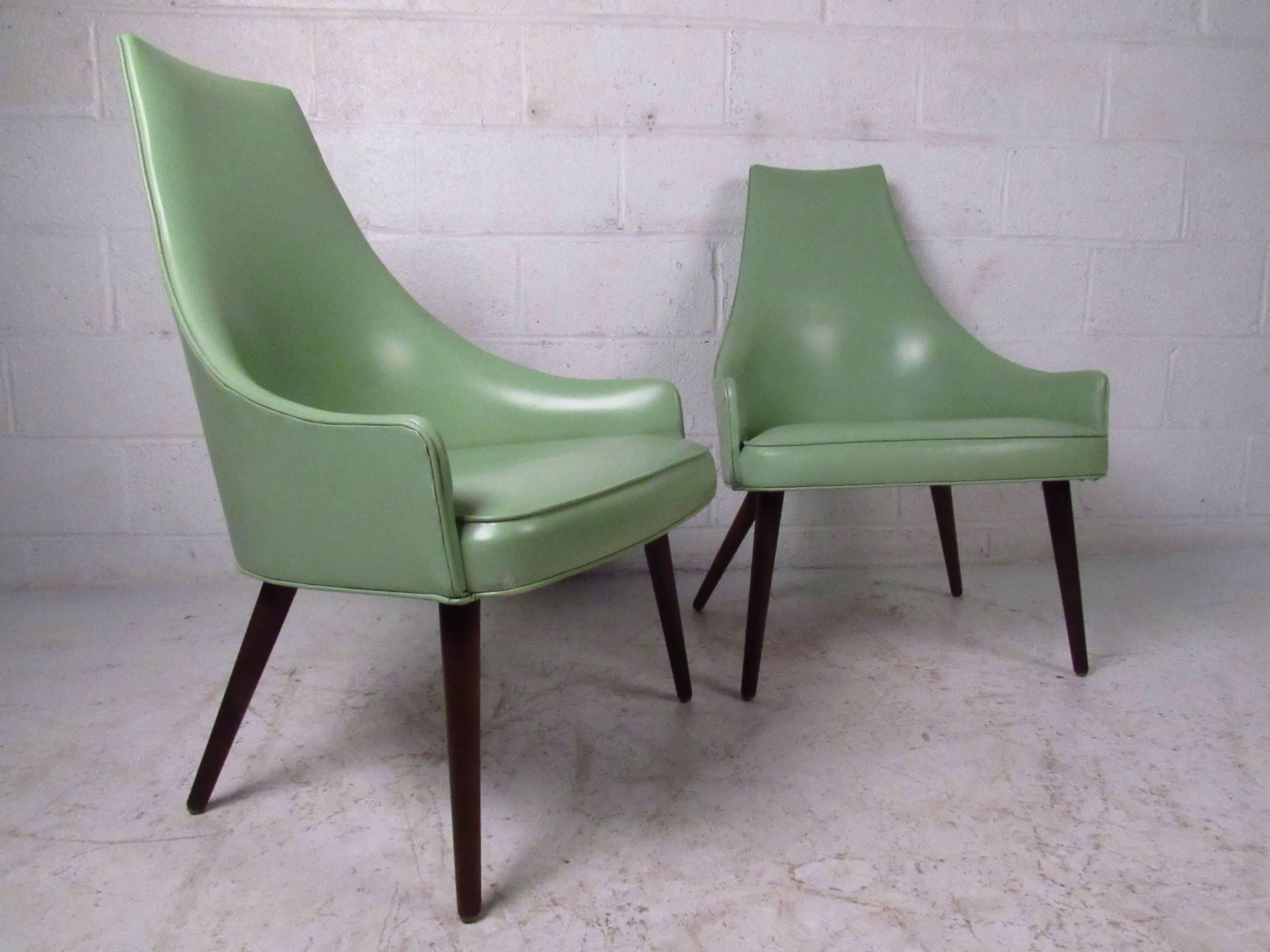 This beautiful vintage pair of lounge chairs feature ample vinyl upholstered seats with unique sculpted high backs. Tapered legs and low profile armrests add to the midcentury style of the set. Please confirm item location (NY or NJ).