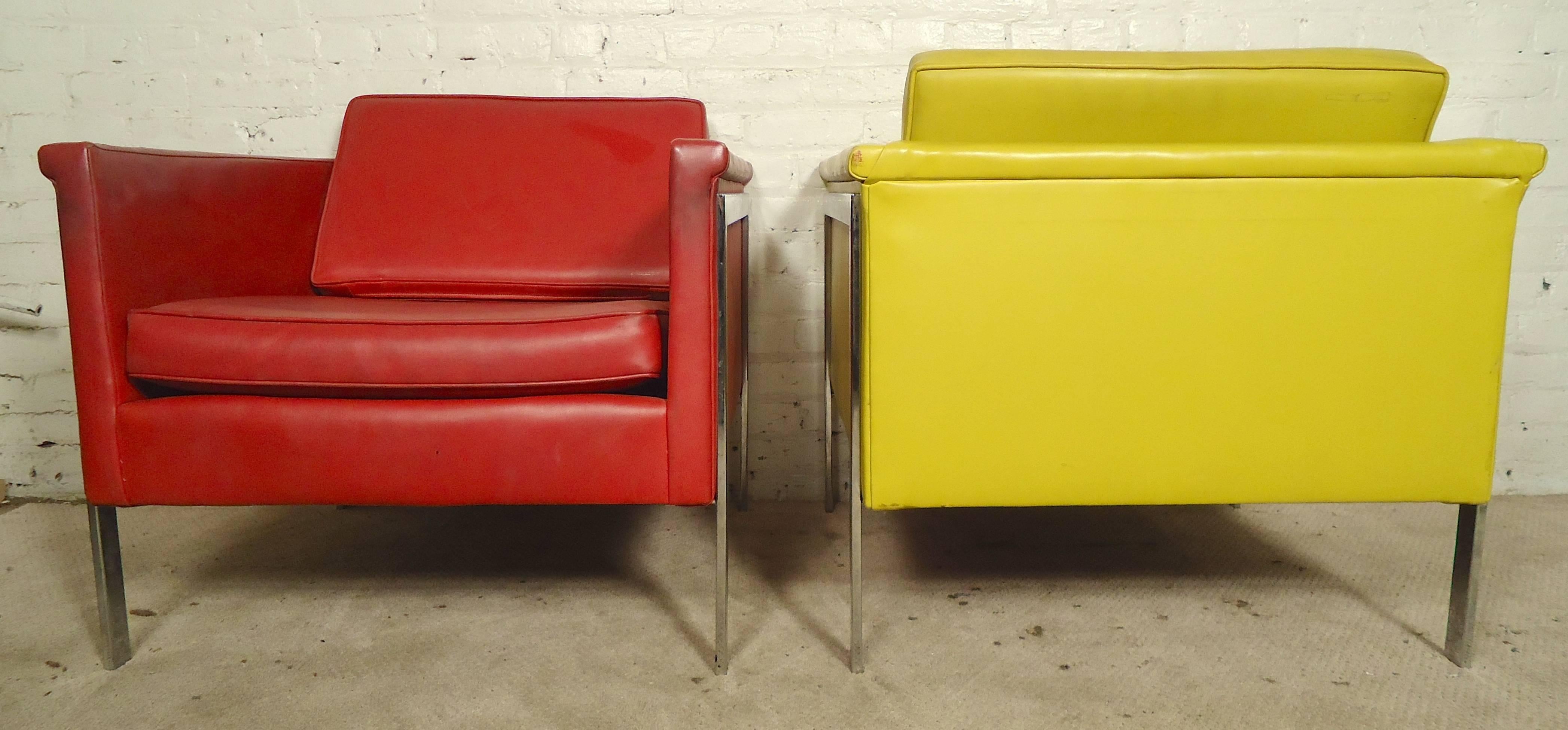 Striking pair of Mid-Century Modern lounge chairs with thick chrome legs that run across the side and back down, giving a nice modern profile. Colorful red and yellow vinyl upholstery make an impressive statement in home or business seating