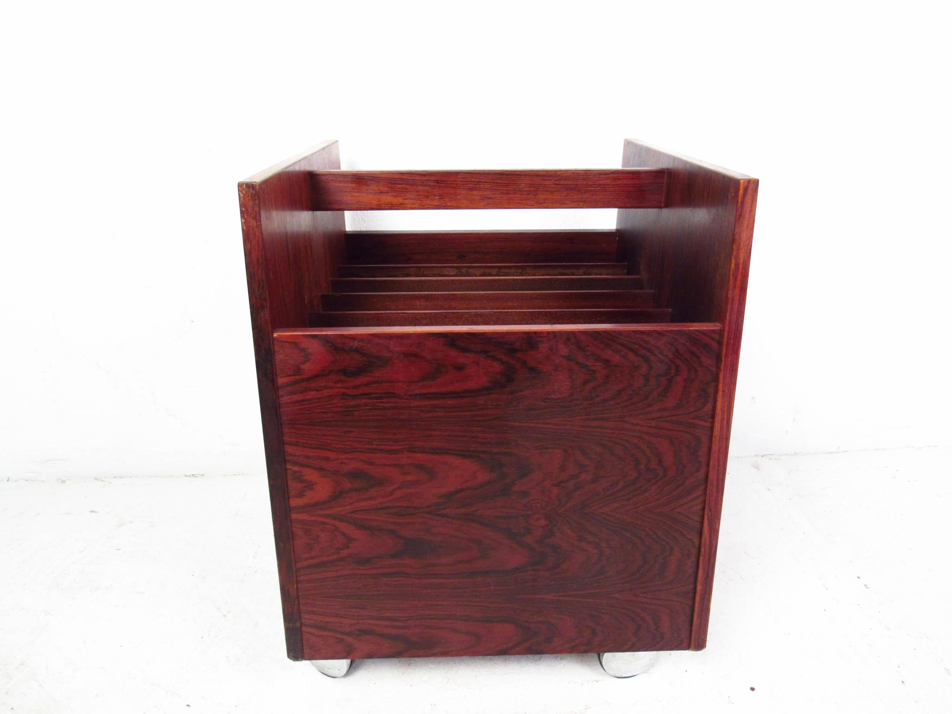 This beautiful midcentury rolling magazine cart has plenty of room for storage and organization. Quality craftsmanship shines through the unique rosewood finish, while the piece rests easily on sturdy casters. Please confirm item location (NY or