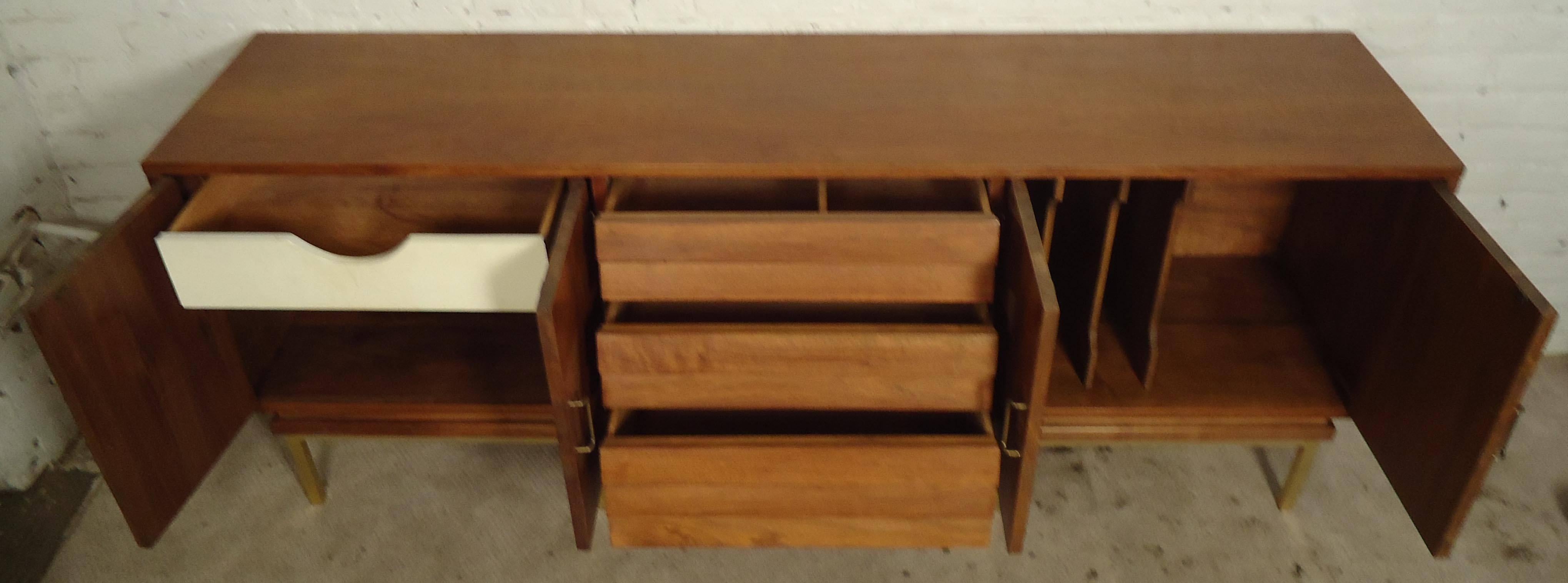 Vintage-modern American Of Martinsville credenza, features three beveled center drawers and two cabinets with sculpted brass handles and legs. 

Please confirm item location NY or NJ with dealer.
