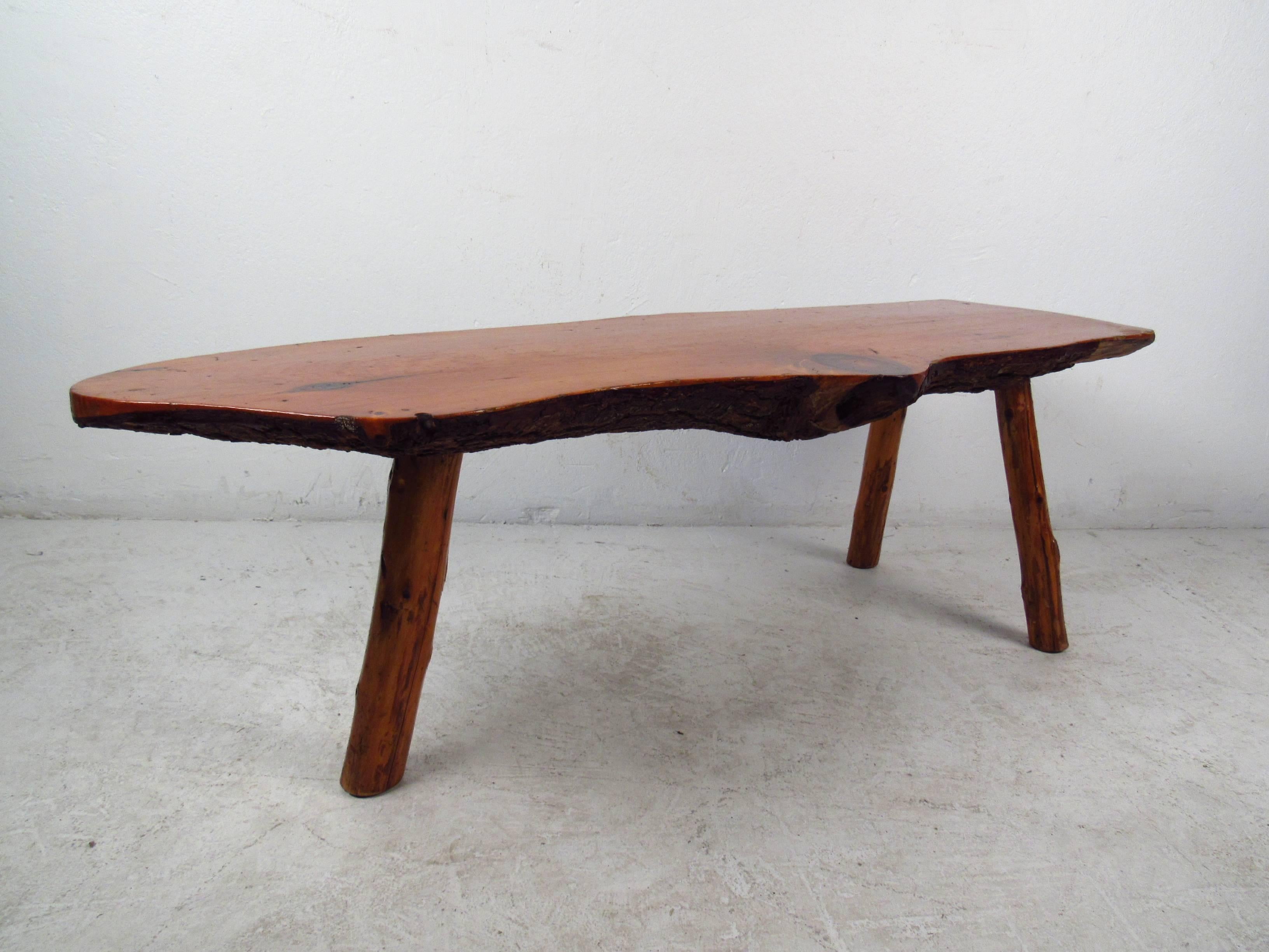 The unique natural wood finish on this vintage coffee table makes this the perfect addition to any home or business environment. This beautiful piece boasts a free form tree slab table top with splayed wood legs. 
(Please confirm item location NY or