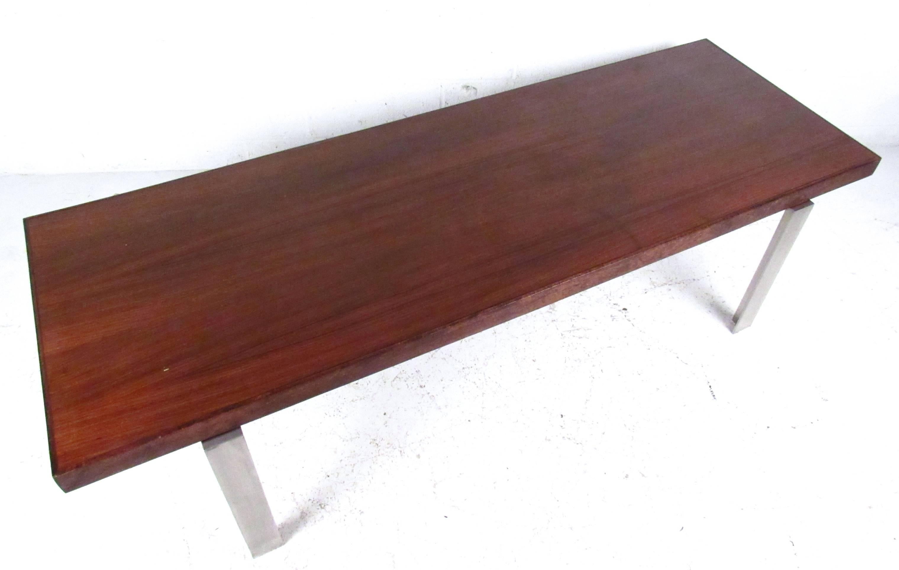 This sturdy vintage coffee table features a thick rosewood top with brushed steel legs. Modern lines and rich wood tones make this a welcome addition to any interior. Please confirm item location (NY or NJ).