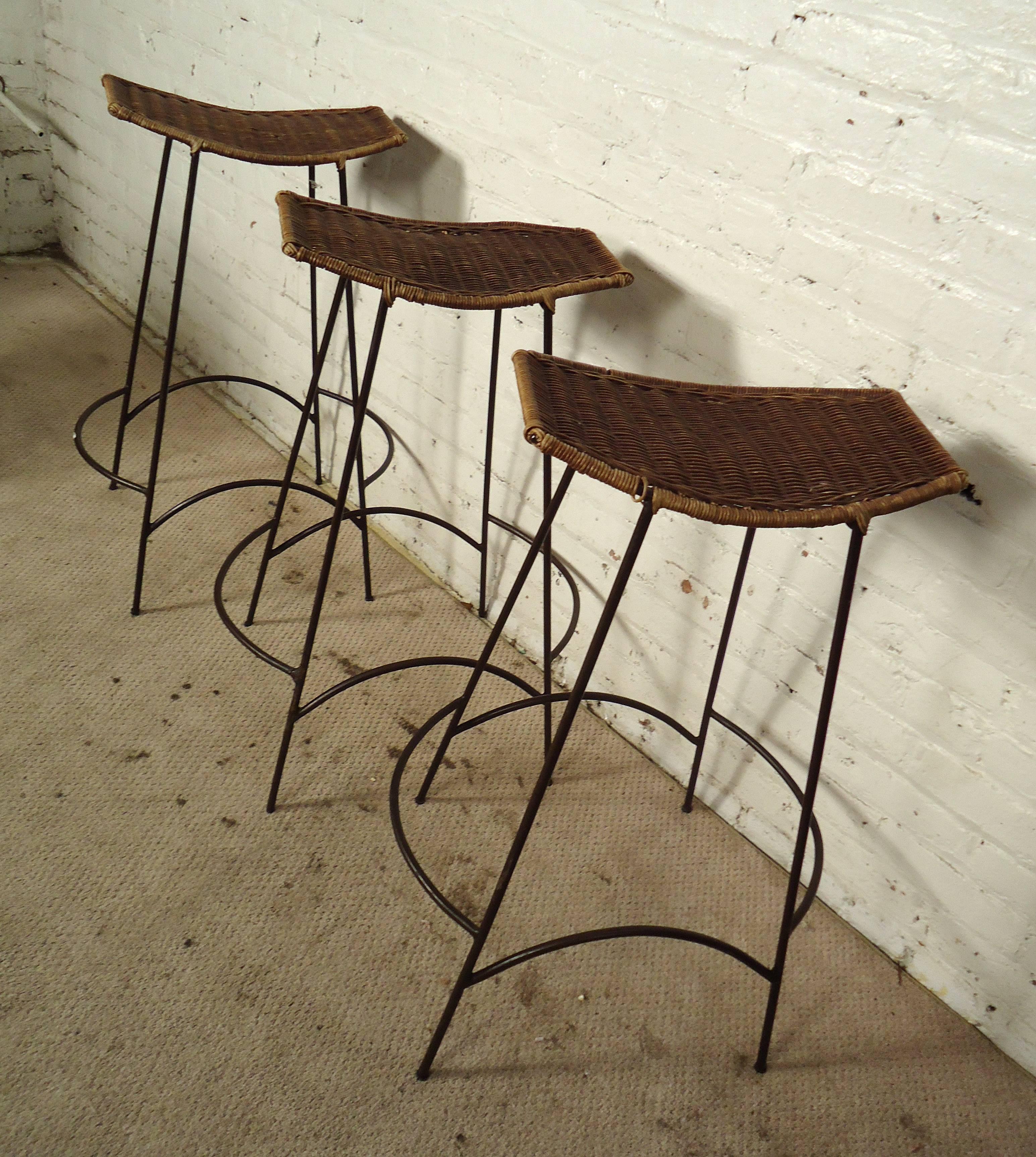 Set of vintage modern Arthur Umanoff-style stools featuring beautifully sculpted iron legs and woven wicker seats.

Please confirm item location NY or NJ with dealer.