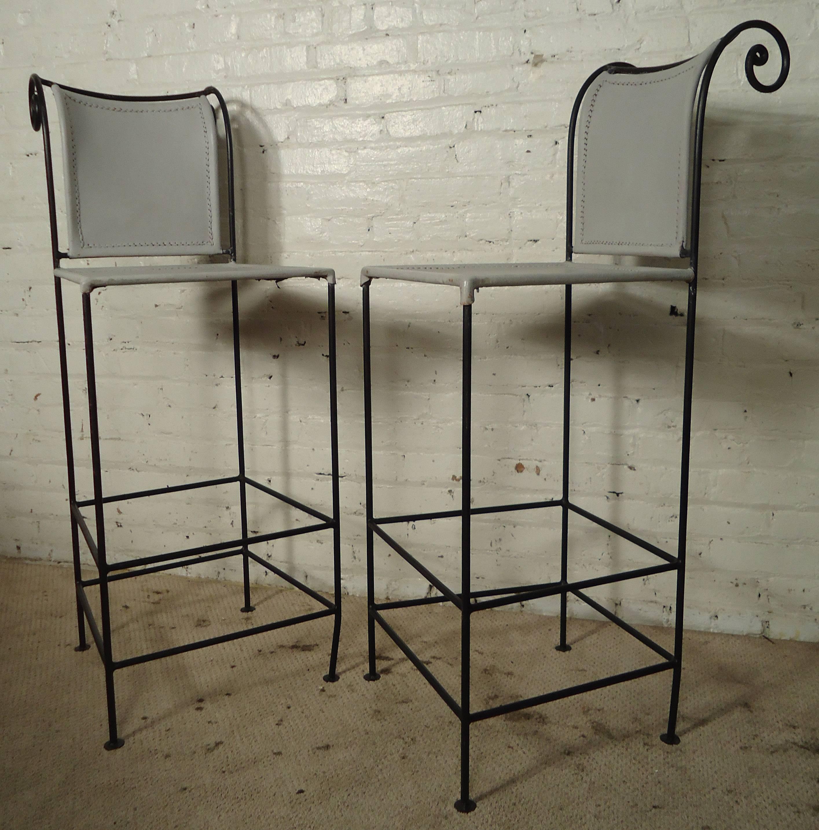 Two vintage-modern stools featuring sculpted iron bases and leather upholstered seats. Designed by Shaver-Howard. (4 similar stools available)