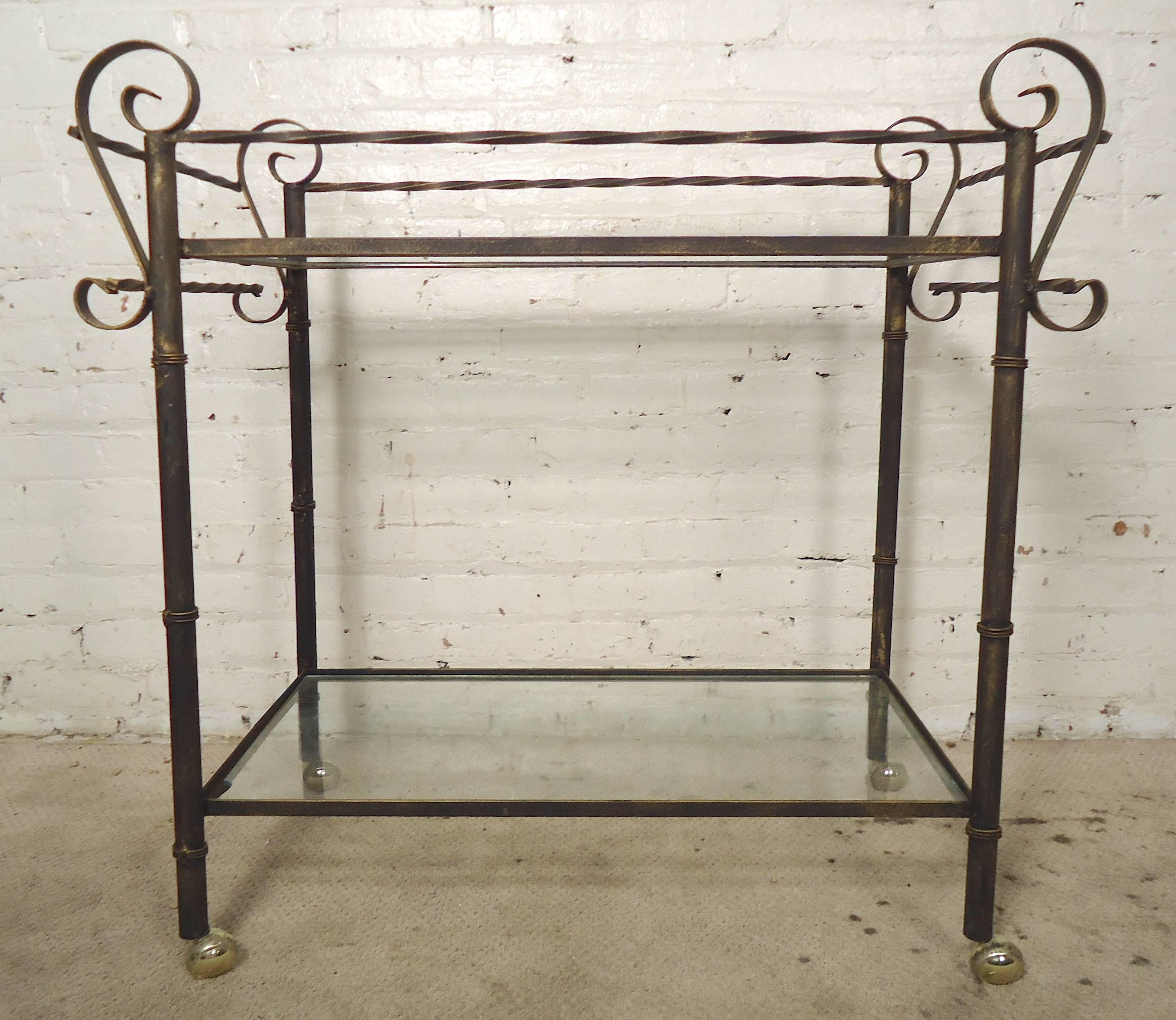 Two level iron cart with scrolled arms and twisting iron rails. Metal has a nice aged patina look, two glass shelves and full rolling casters.

(Please confirm item location - NY or NJ - with dealer)

