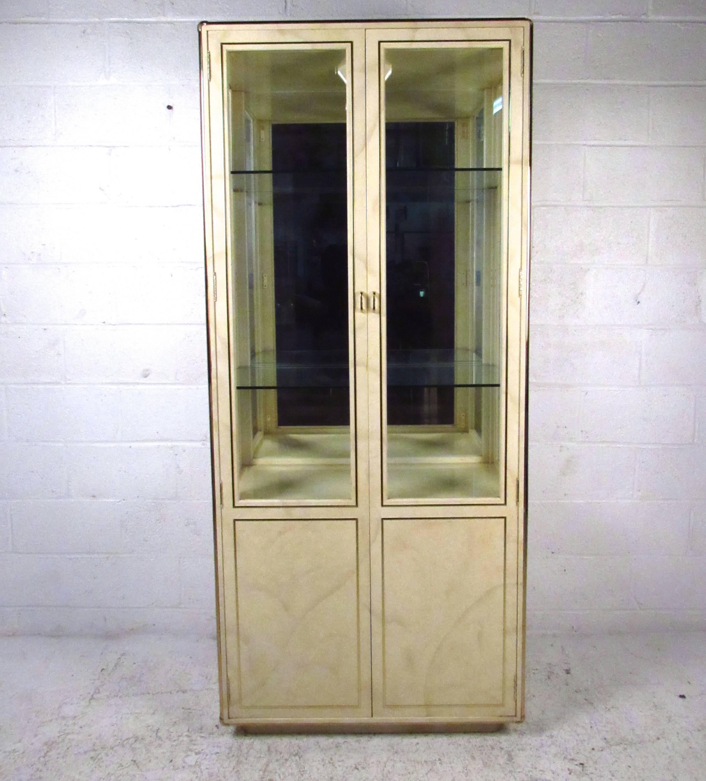 This beautiful goatskin vitrine cabinet is an elegant example of the vintage design quality John Stuart is so well-known for. Cabinet lighting, brass trim, and a mixture of hidden and display storage make this a versatile and stylish addition to any