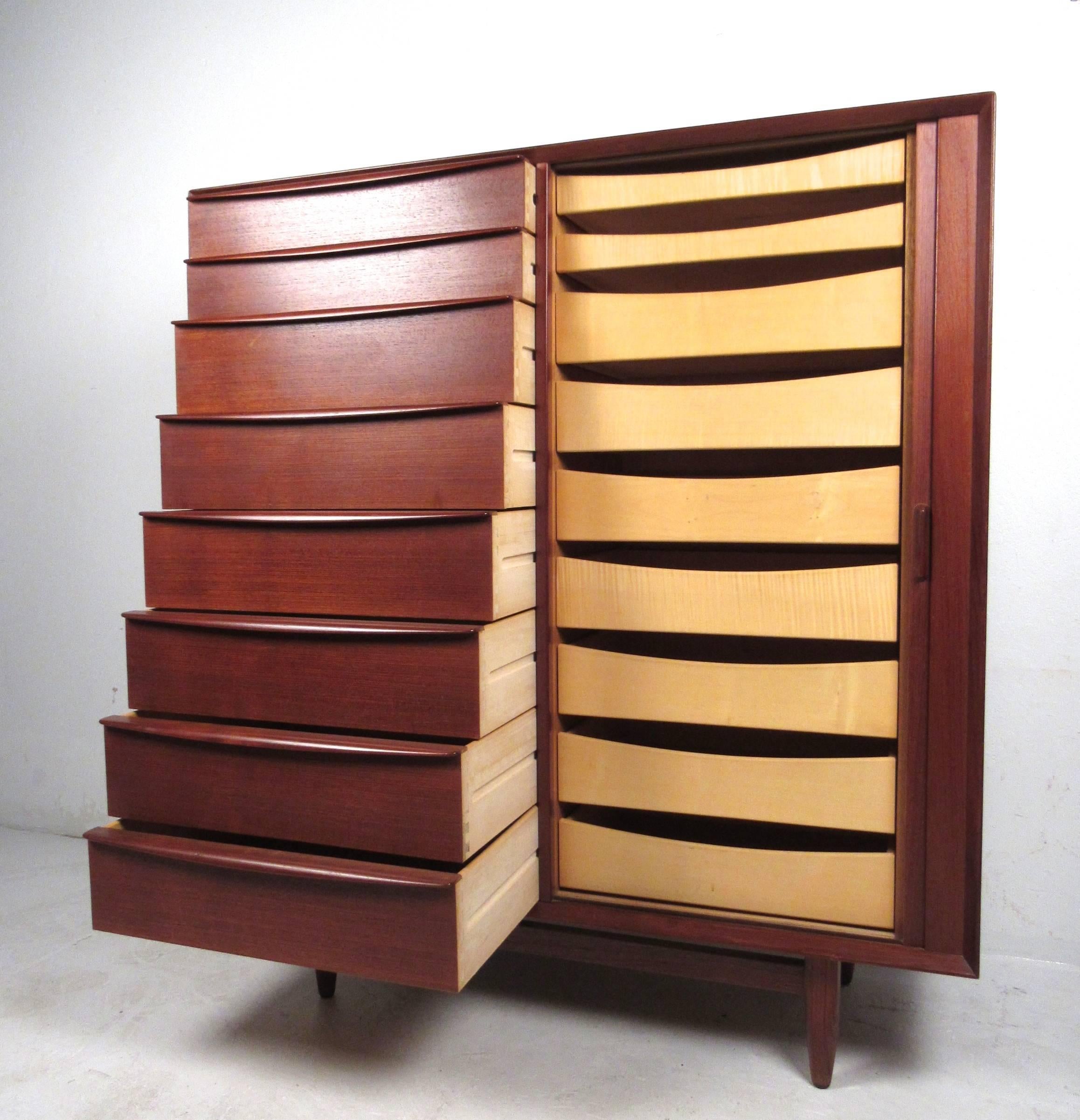 This gorgeous teak dresser by Falster boasts a beautiful teak finish, complete with dovetailed carved drawer pulls, tambour door, tapered legs, and plenty of storage. Unique piece perfect for any interior, please confirm item location (NY or NJ).