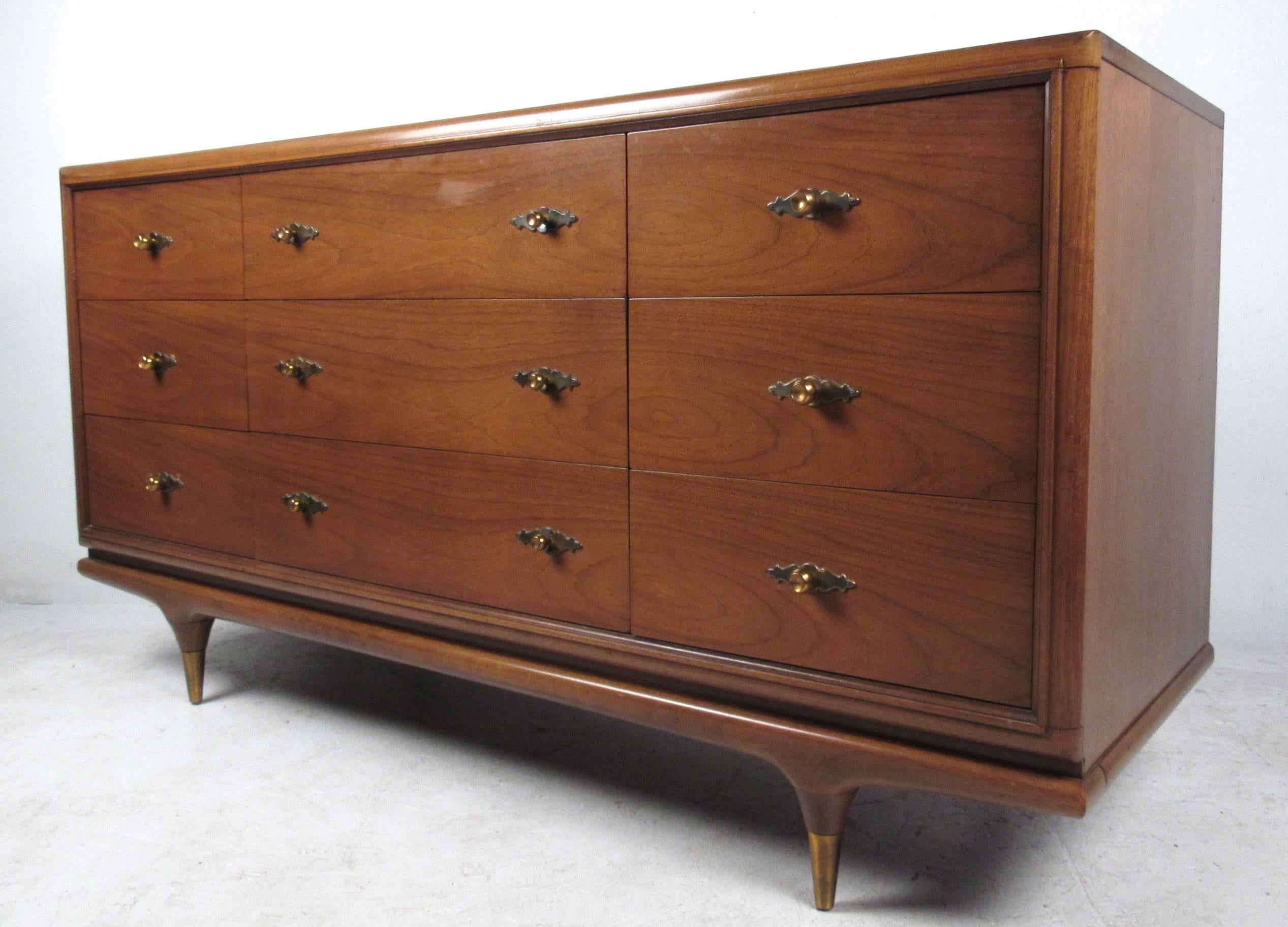 This beautiful nine drawer walnut dresser features the classic style of the Continental line produced by American manufacturer Kent Coffey. Ornate drawer pulls, tapered legs, and brass tip feet add to the unique appeal of the piece. Please confirm