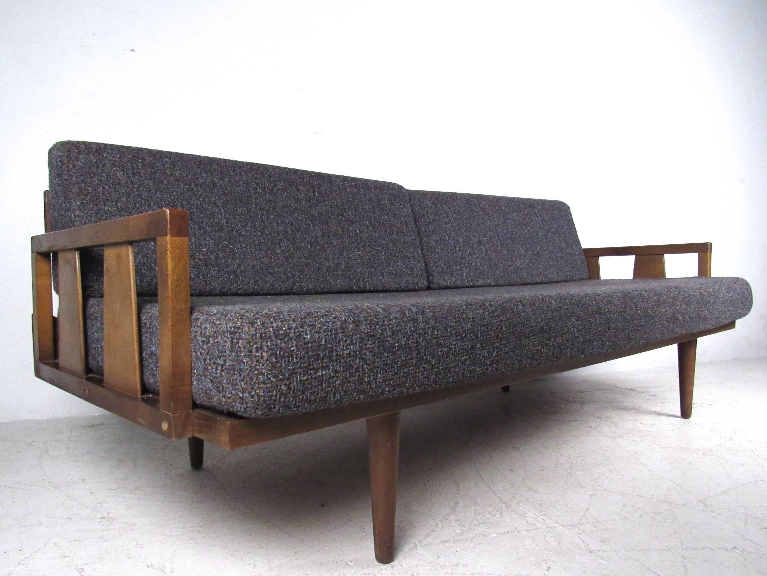 This vintage upholstered sofa offers a wide seating area and easily converts to a daybed by removing the seat back cushions. Tapered legs, cutaway arm rests, and comfortable versatility make this a unique addition a variety of seating arrangements.