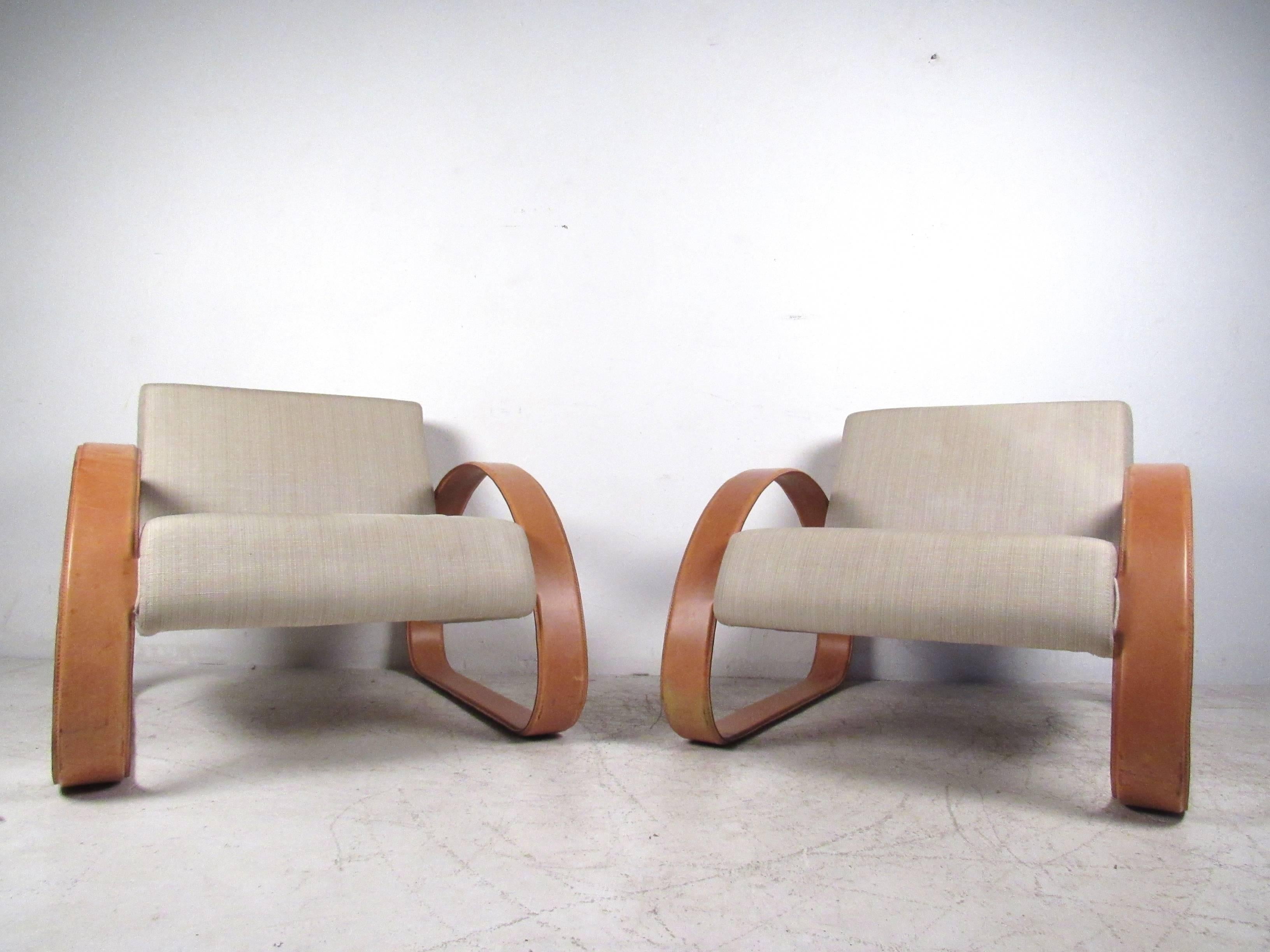 This stylish pair of Mid-Century style lounge chairs by Armani Casa make an impressive addition to any interior. The unique leather frame compliments the wide and accommodating seats, while angled backs add comfortable support. Please confirm item