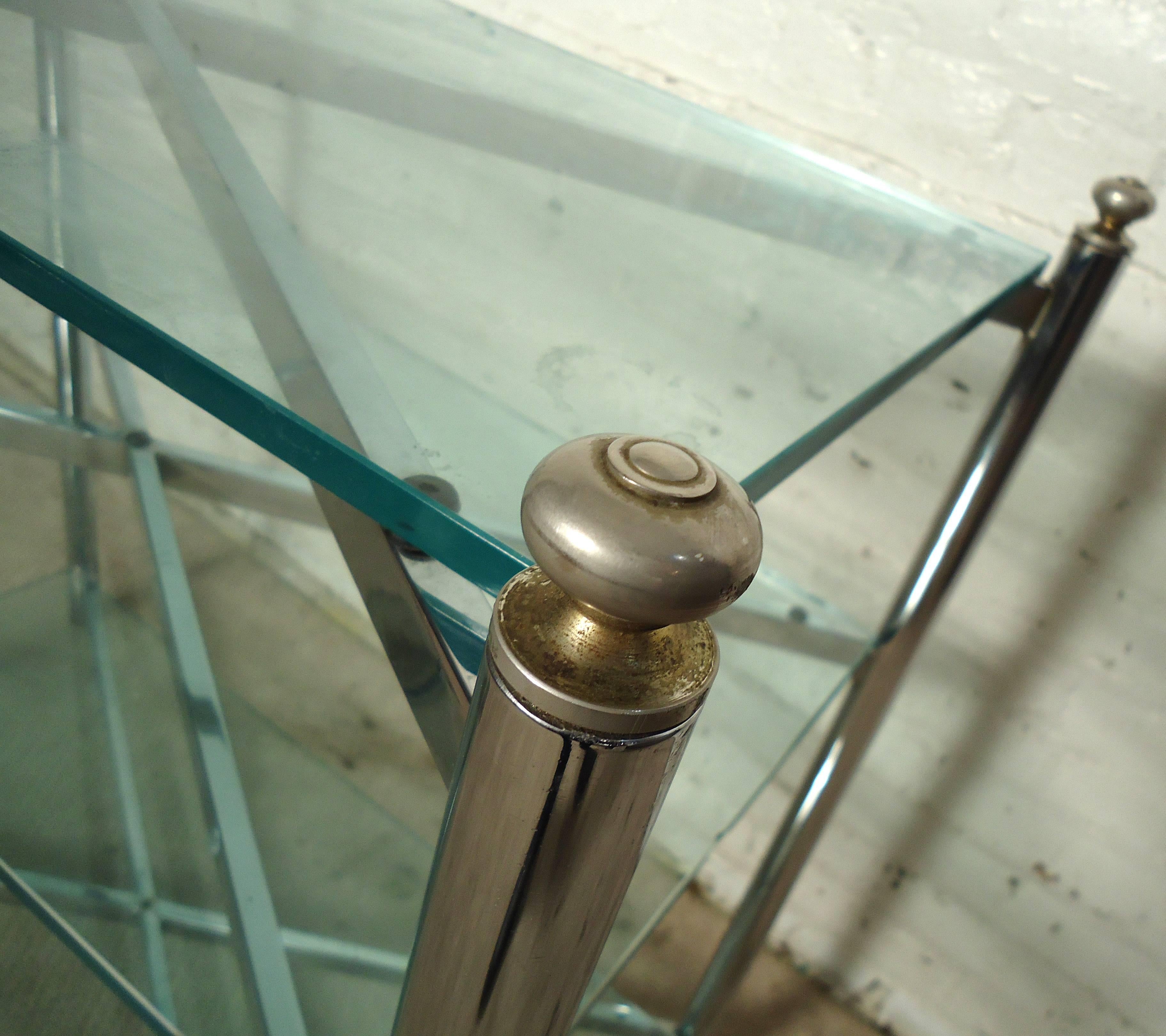 Consolle vintage-moderna a tre livelli con cornice cromata e finiture in ottone, tre inserti in vetro poggiano su snodi a x scolpiti. Realizzato nello stile di Mastercraft.

Si prega di confermare la posizione dell'articolo NY o NJ con il
