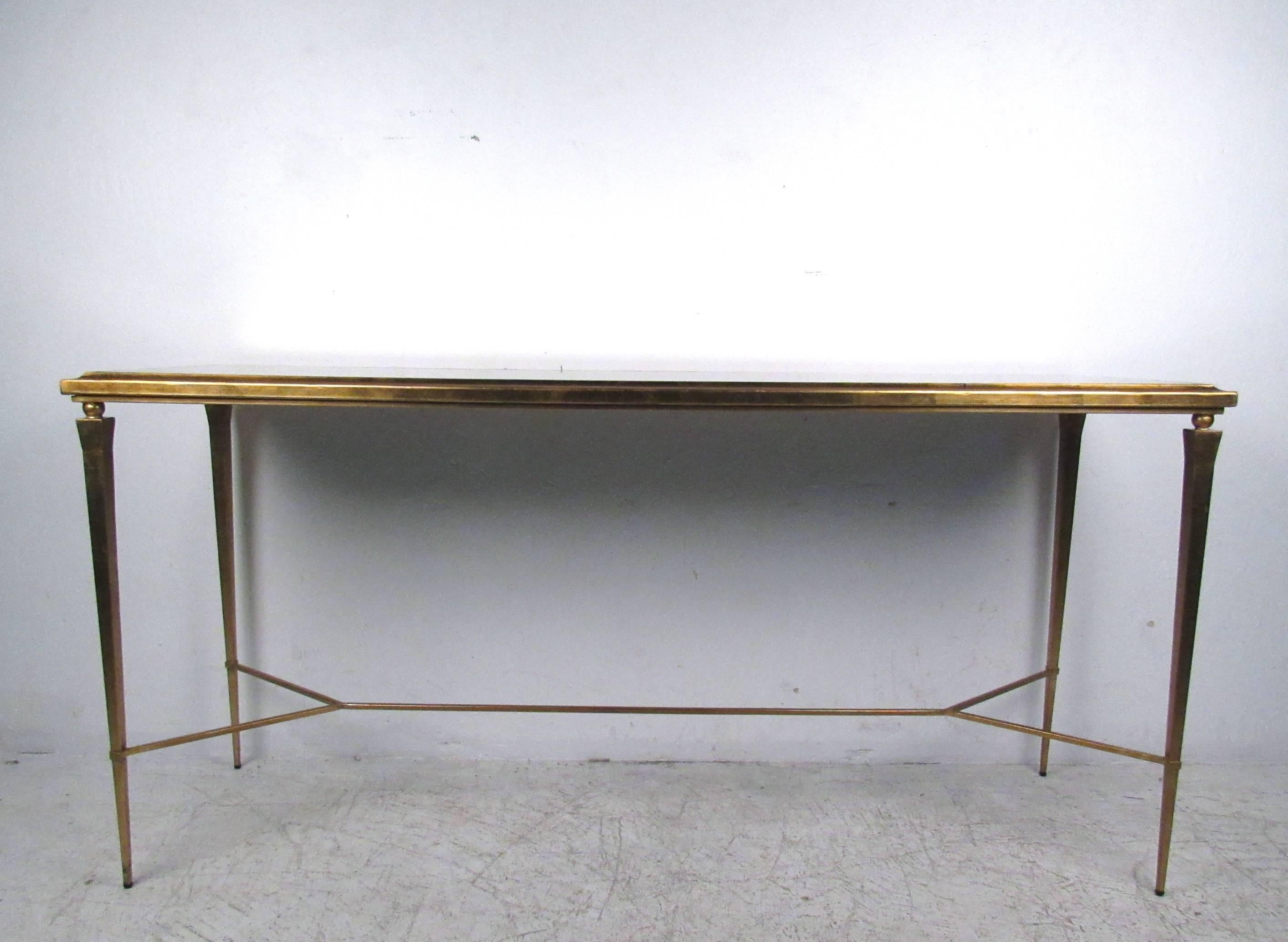 This beveled mirror console table features treated mirrored top with gold painted tapered leg frame. Stretcher adds stability to this elegant and impressive table, unique addition for a variety of interiors. Please confirm item location (NY or NJ.)
