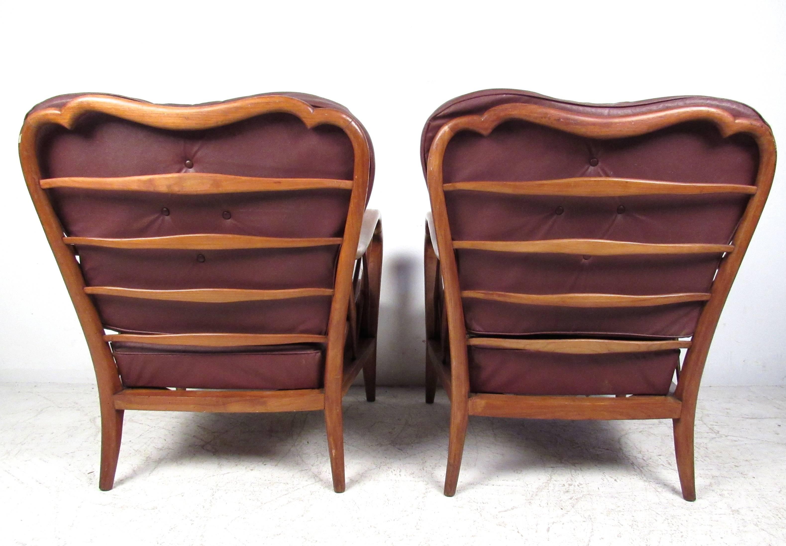 This uniquely styled pair of vintage wood frame armchairs feature a rare collection of features, including sculptural seat backs and frames, with. Tapered legs, shaped seat cushions, and intricate design throughout the woodwork showcase the