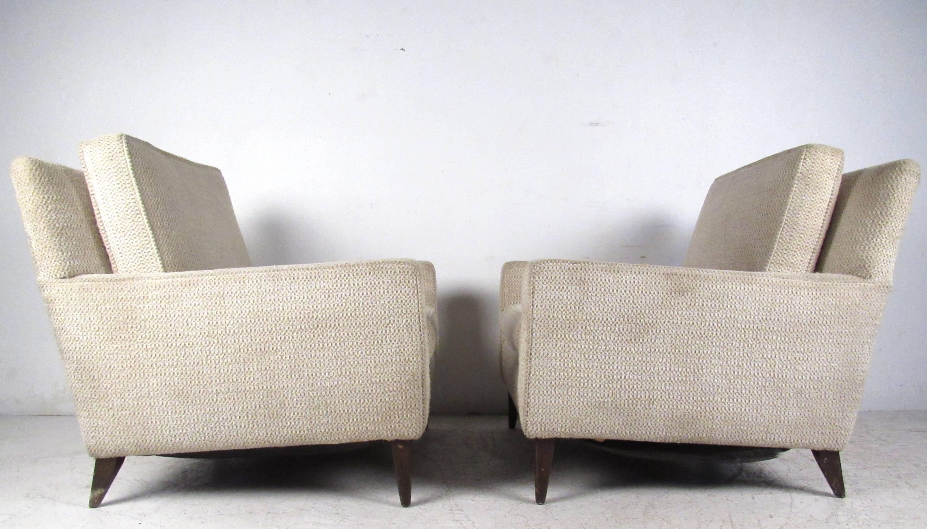 This vintage pair of upholstered lounge chairs make a practical yet stylish addition to seating in any setting. The chairs feature tapered legs, comfortable design, and mid-century charm. Please confirm item location (NY or NJ). 
