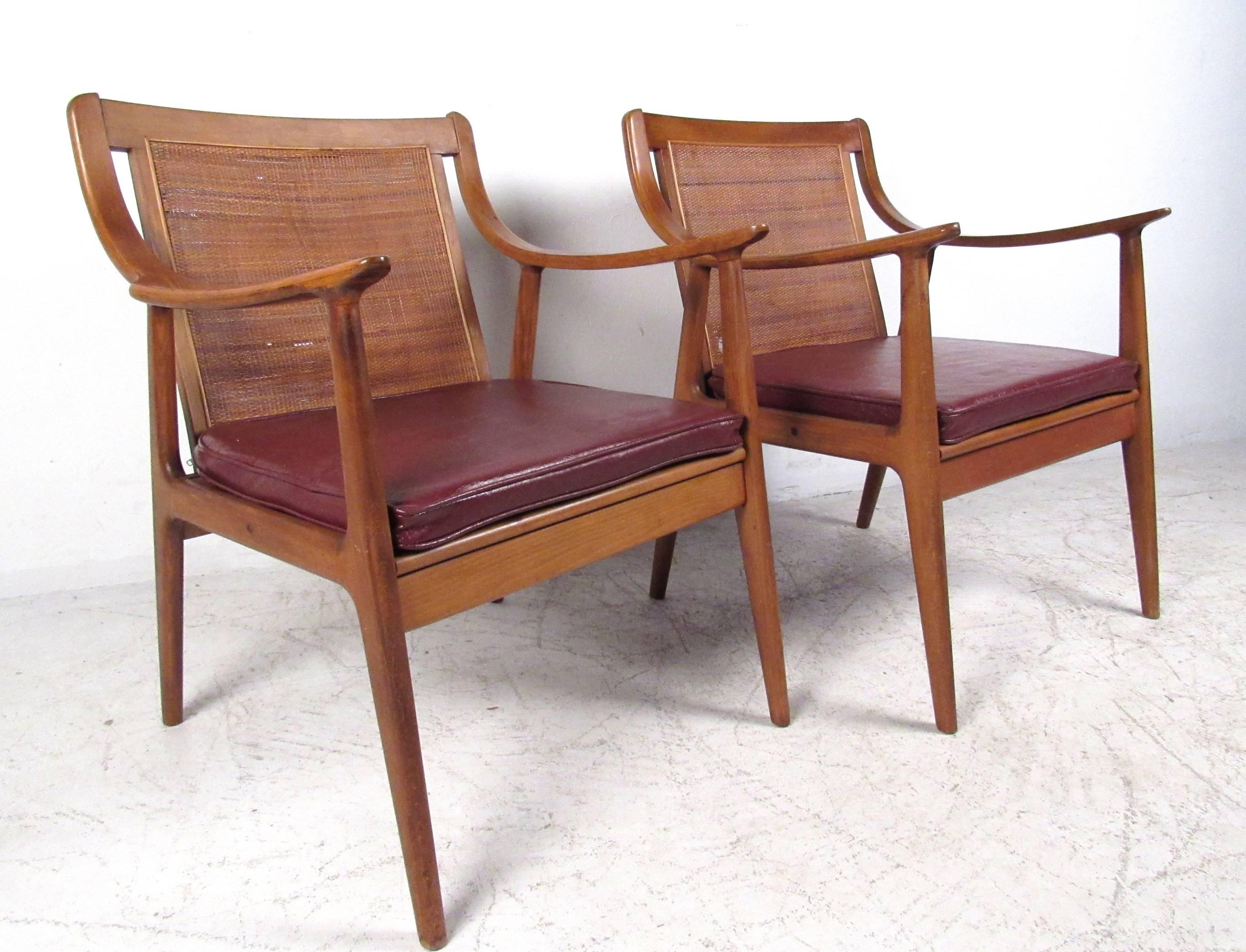 This stylish pair of cane back chairs make a comfortable vintage addition to any interior. Wonderfully crafted chair frames feature sloped style sculptural arm rests, upholstered seats, and tapered legs. Please confirm item location (NY or NJ). 