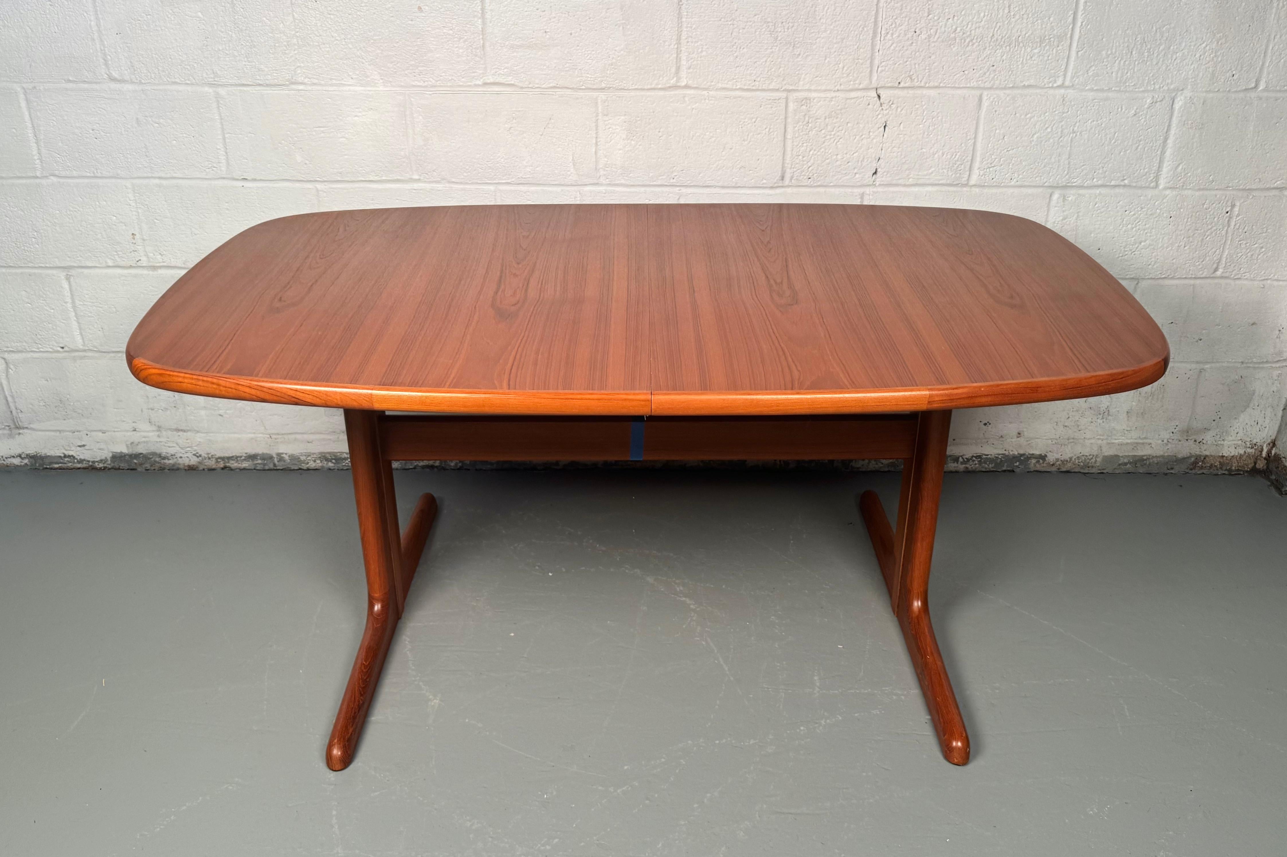 Elevate your dining experience with this exquisite vintage teak dining table, featuring two convenient leaves that adapt to your needs. A timeless statement piece of mid-century craftsmanship, it's ideal for intimate dinners or festive