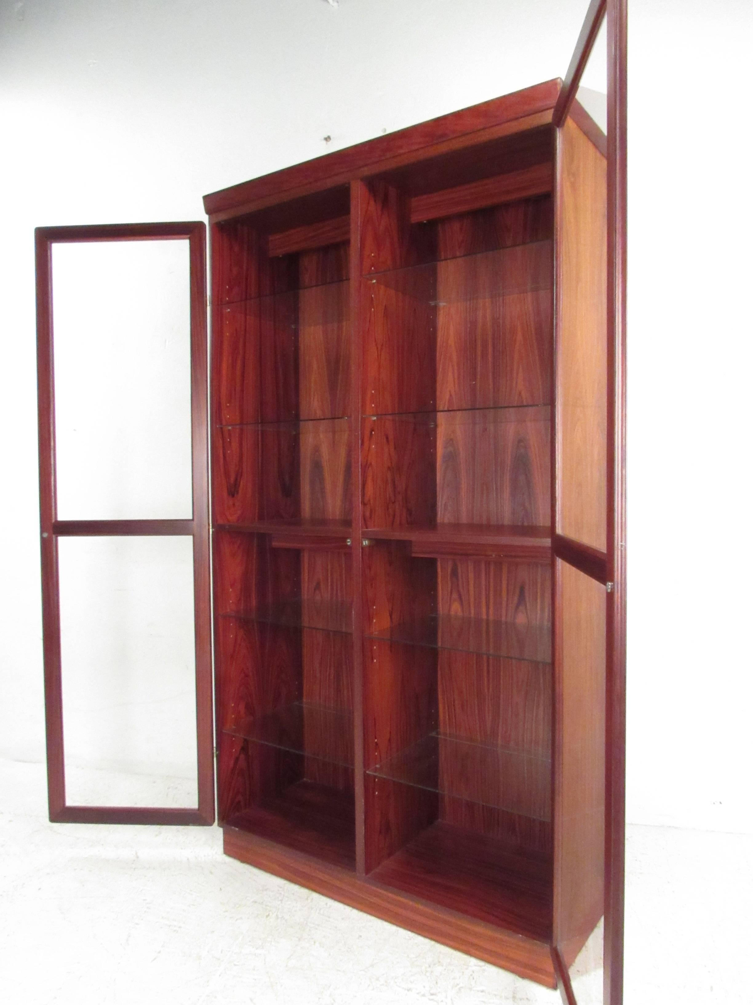 Beautifully constructed rosewood display cabinet by noted Danish manufacturer Skovby. Unit has eight adjustable glass shelves (with plate grooves), two fixed wood shelves and two interior lights. Skovby label with Danish Quality Control Makers Mark.