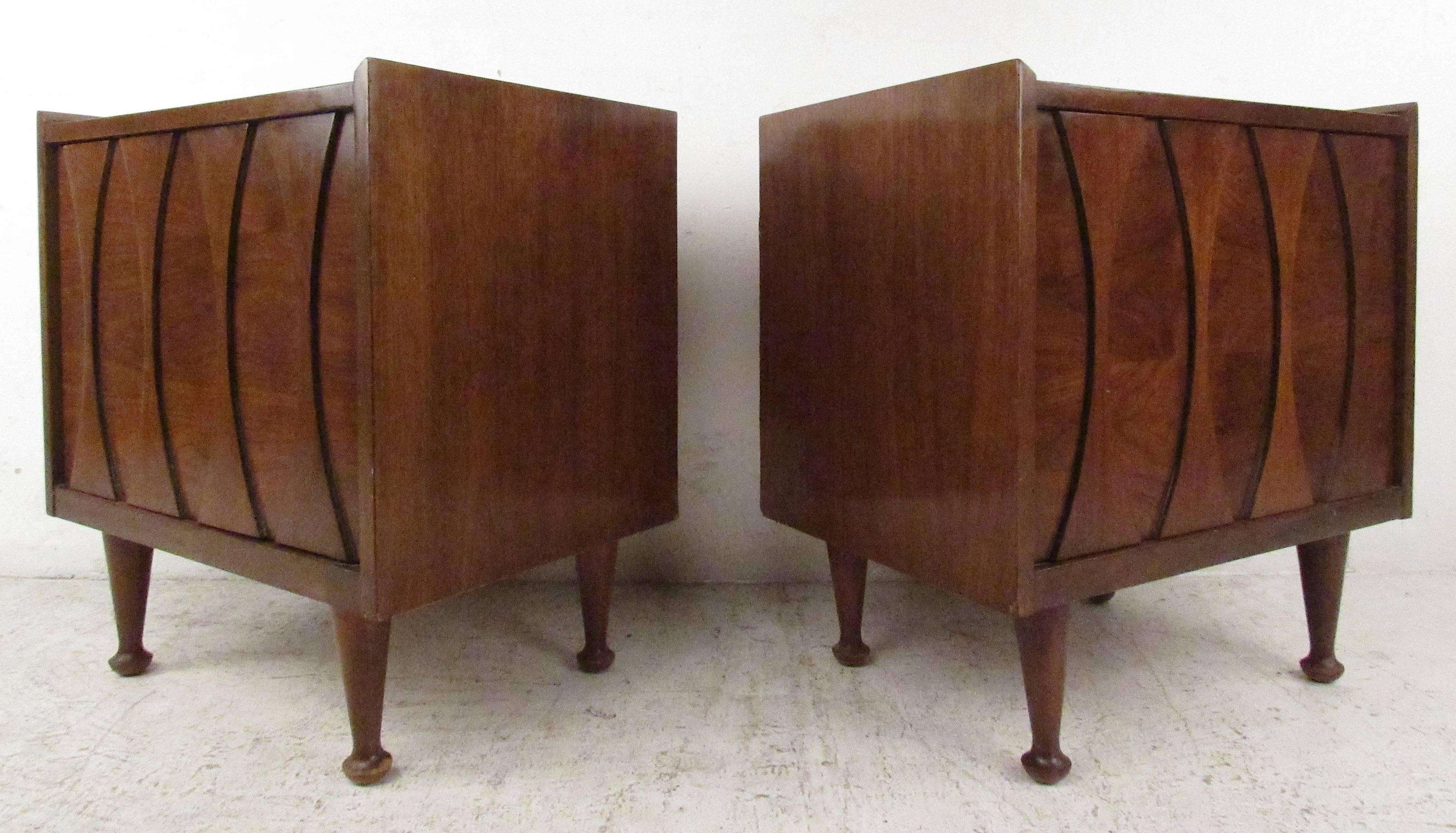 Pair of walnut nightstands with stationary shelf by Hoke Wood Products. Mid-Century Modern bedside end tables with sculpted applied fronts, tapered drumstick legs, and rich vintage wood finish. Please confirm item location (NY or NJ) with