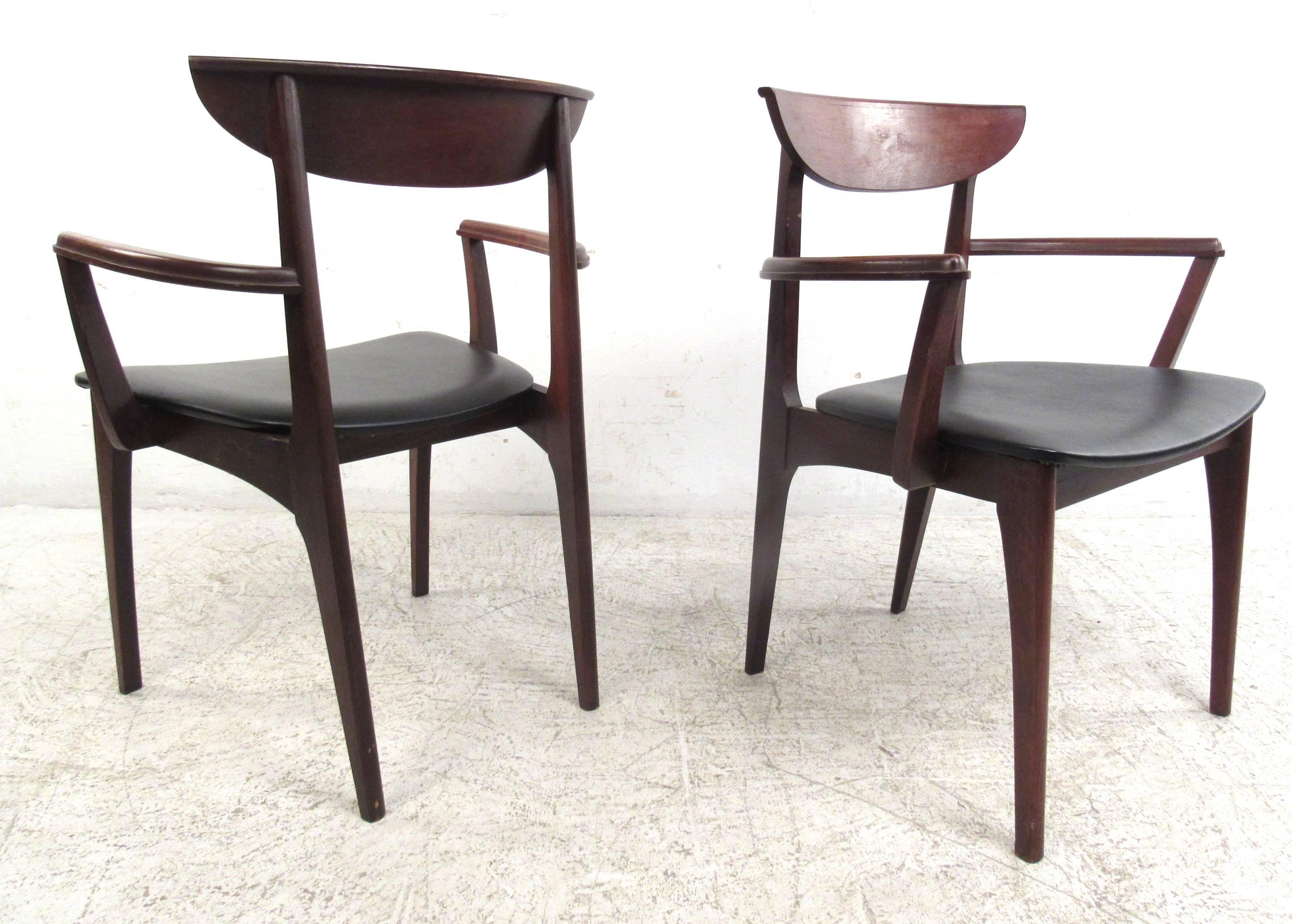 Set of six American Mid-Century dining chairs in walnut with black vinyl seats. Please confirm item location (NY or NJ) with dealer.