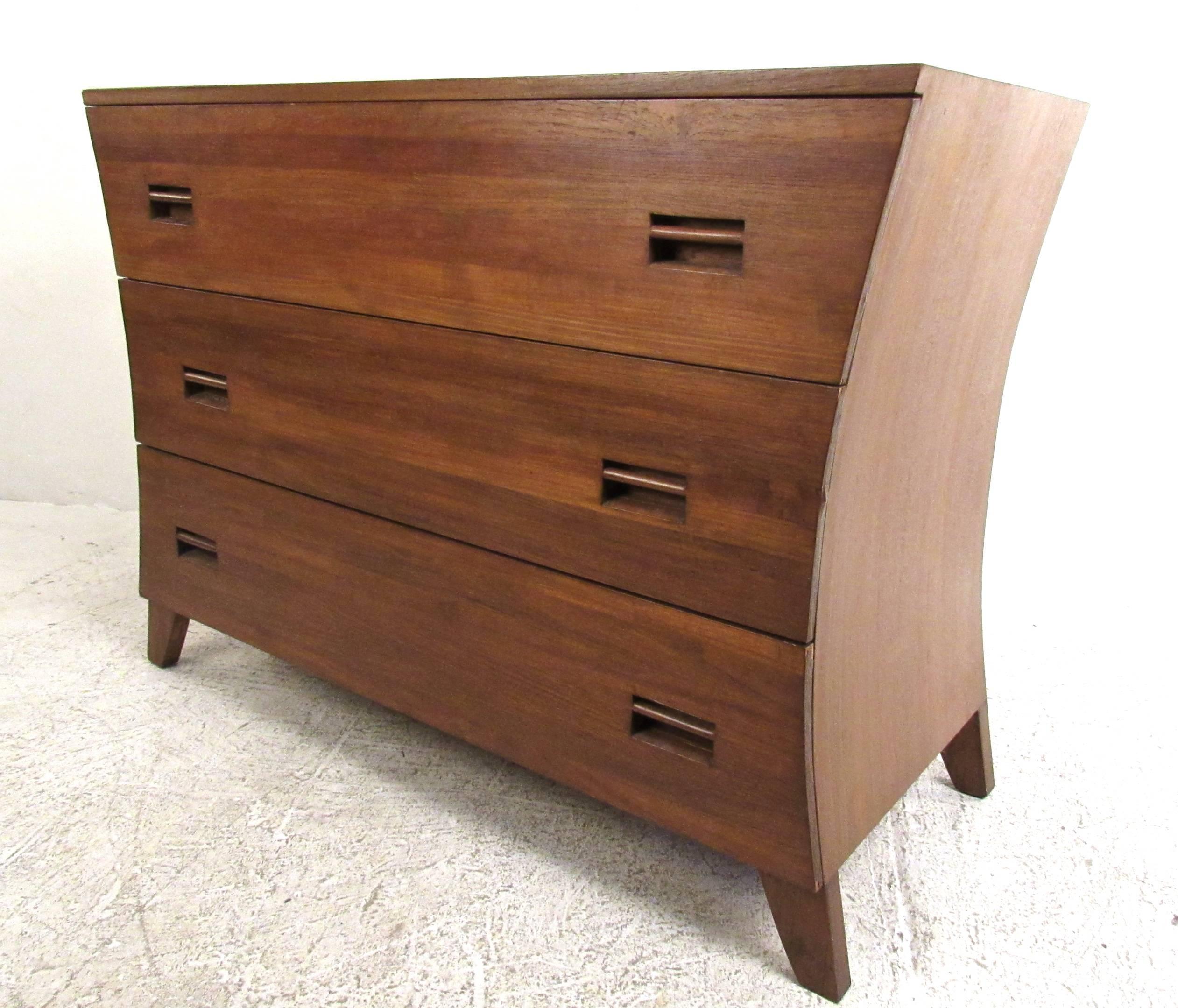 This Mid-Century pair of three drawer dressers make a wonderful complimentary set of storage pieces for any setting. Sculpted chests feature unique concave sides with recessed pulls in a rich teak finish. Vintage dresser set makes a great addition