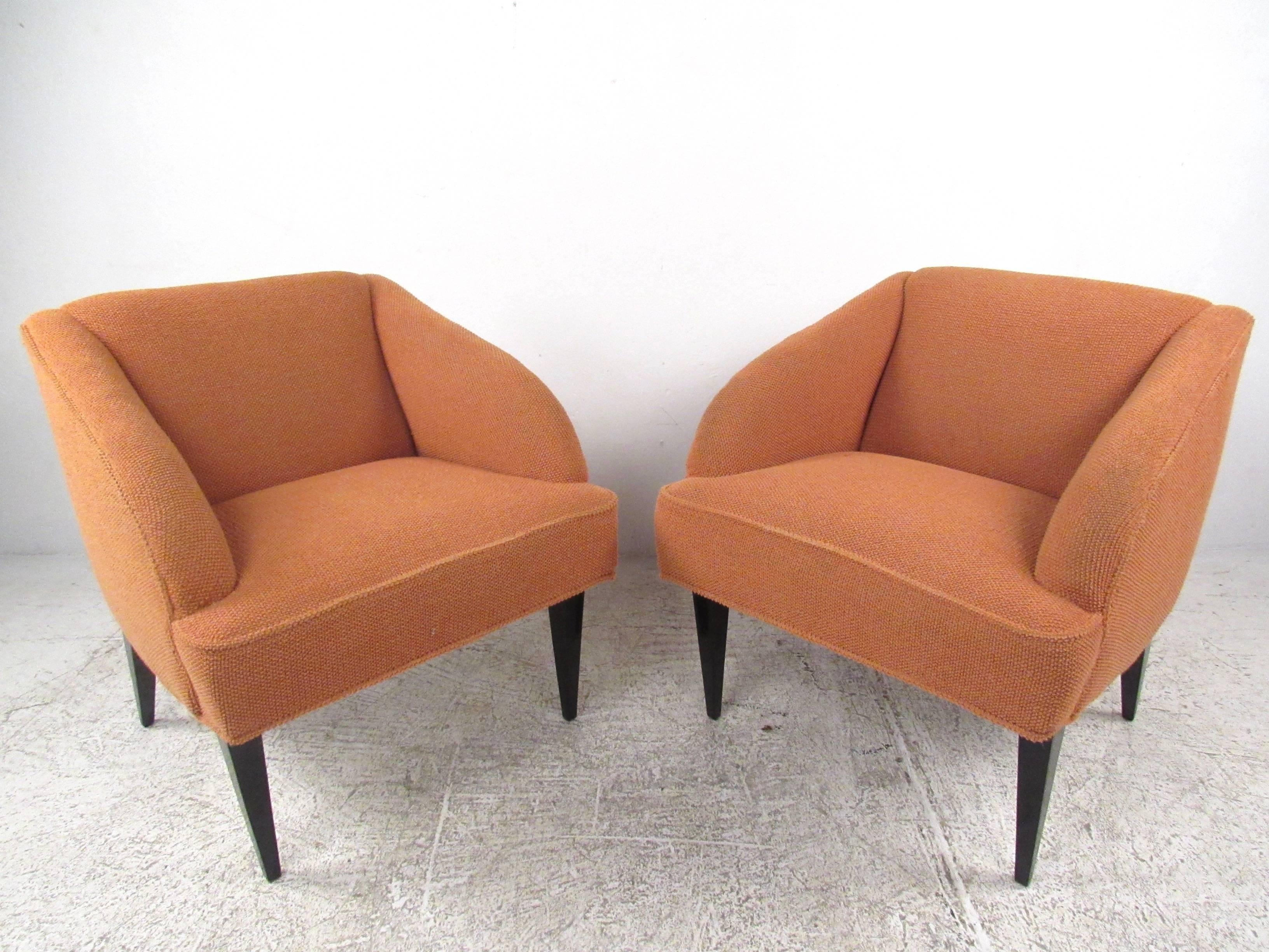 This unique pair of mid-century modern lounge chairs features comfortable rounded seat backs, tapered black lacquer legs and uniquely modern sculpted design. Impressive pair of upholstered lounge chairs makes a stylish addition to any seating