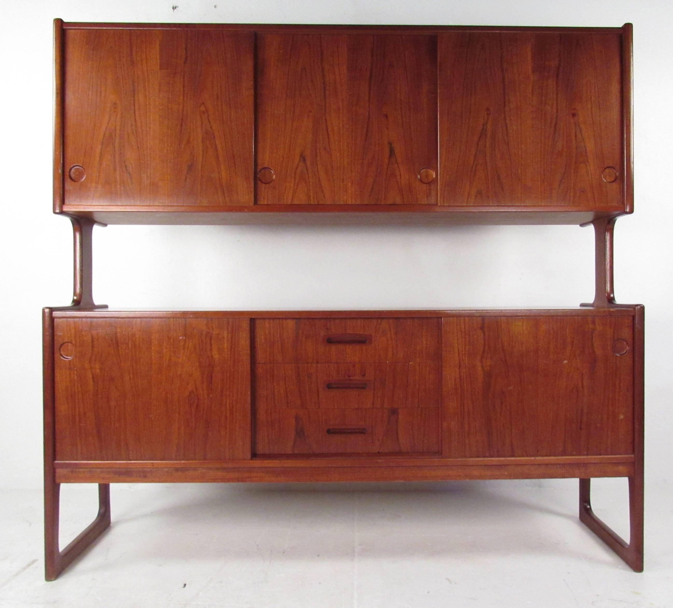 Beautifully constructed bi-level sideboard with sled legs, multiple storage drawers/compartments, adjustable shelves and finished back. Impressive statement piece with stunning teak finish and quality mid-century modern construction. Handsome and