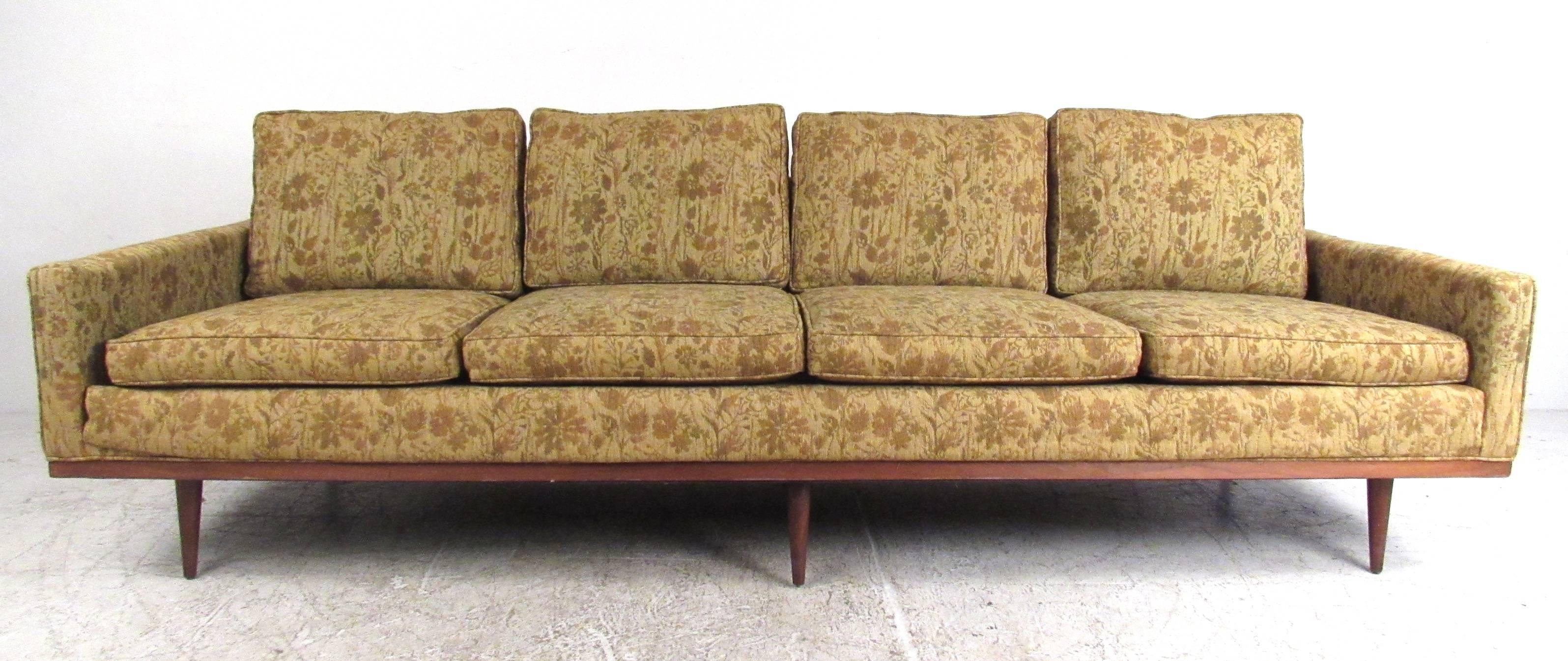 This exquisite vintage sofa features a stunning four seat design with six legs for added support. Wood trim, tapered post legs and classic Milo Baughman style add to the Mid-Century appeal of this long sofa. Please confirm item location (NY or NJ).